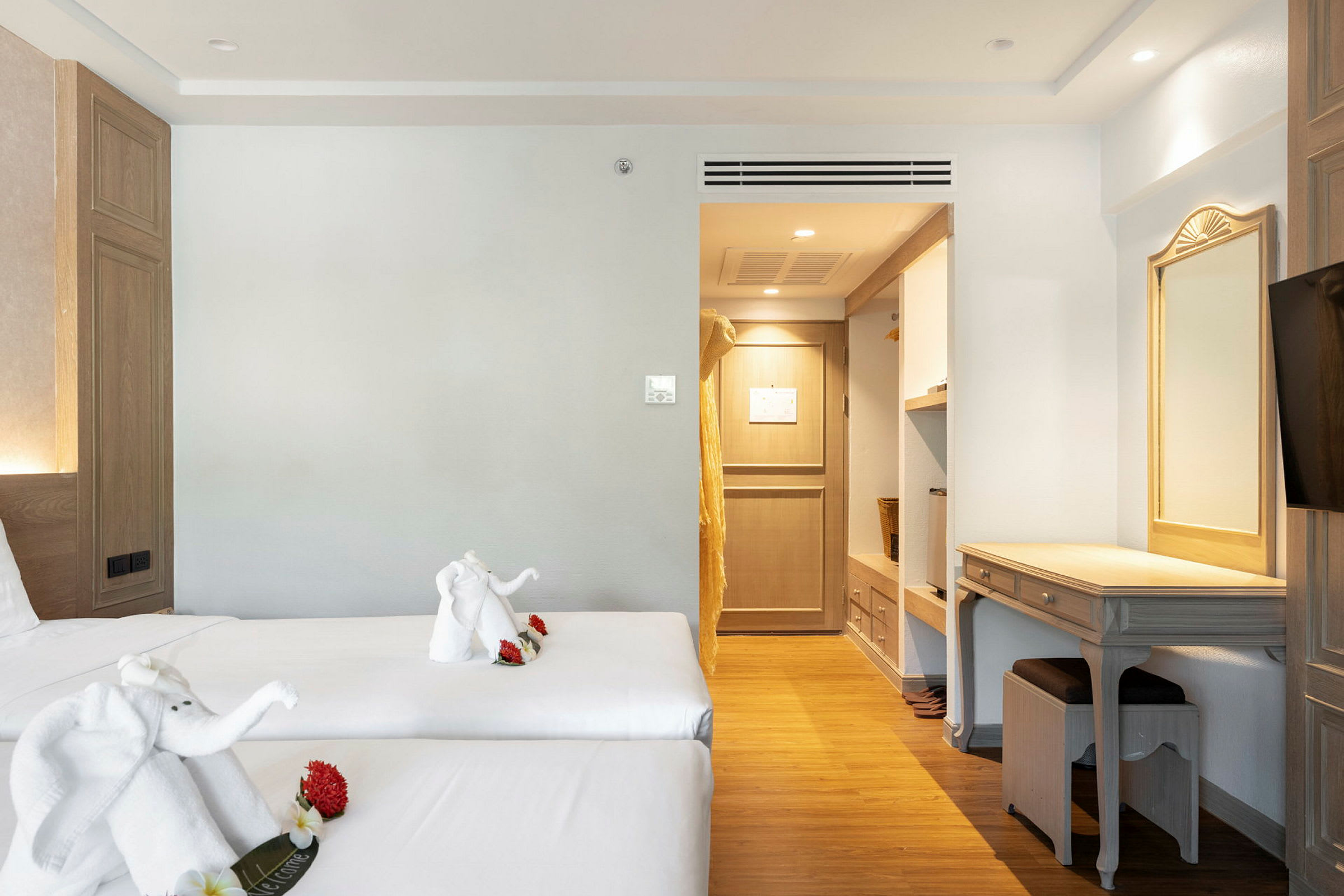 Hotelværelse med to enkeltsenge, dekoreret med håndklædefigurer. Indretning inkluderer skrivebord og adgang til garderobe. (AI-genereret tekst)