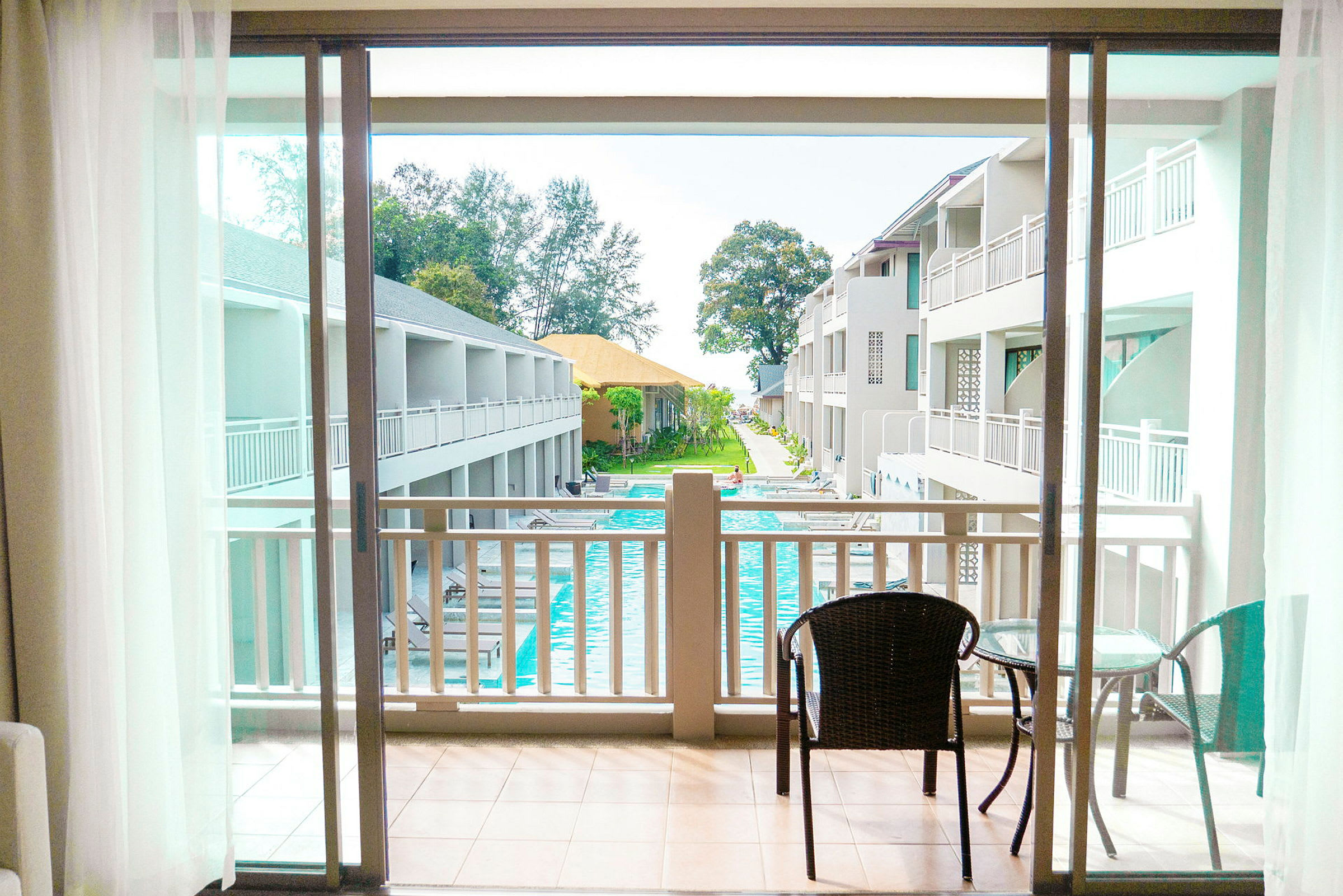 Udsigt fra balkon mod poolområde og hotelbygninger. (AI-genereret tekst)