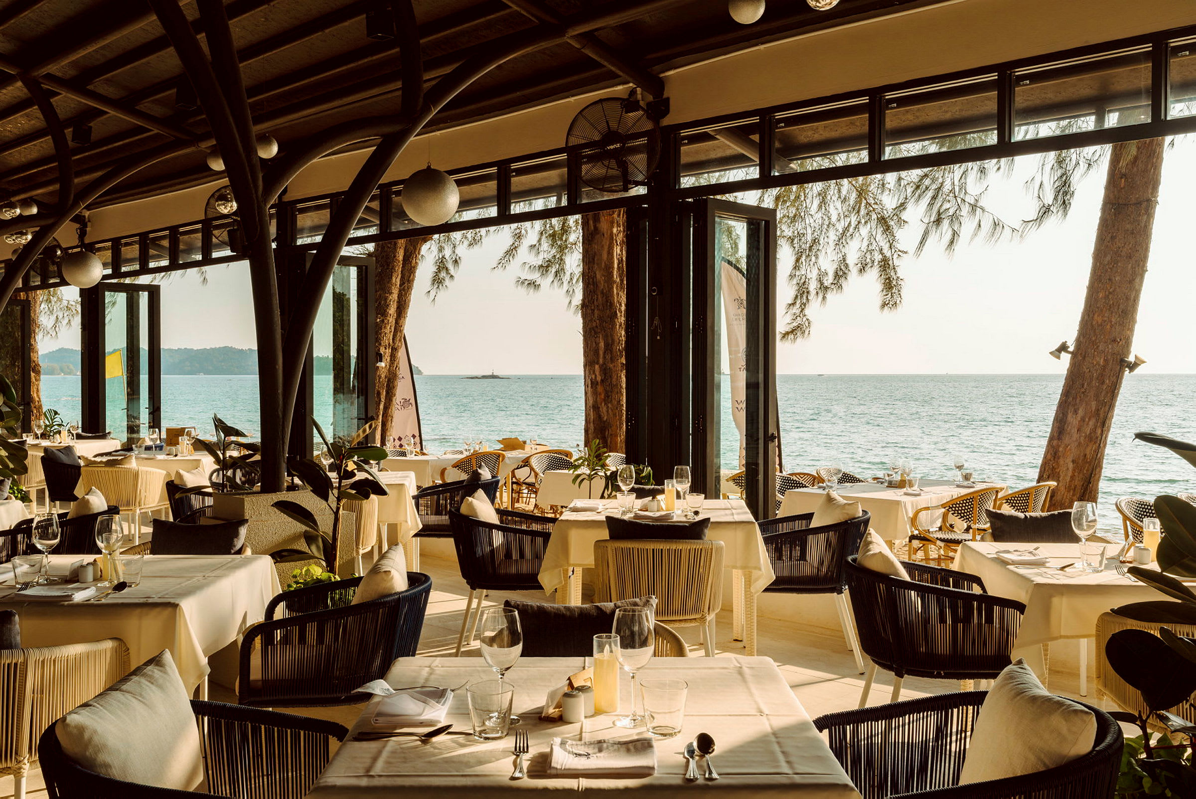 En restaurant med dækkede borde og udsigt over havet. (AI-genereret tekst)