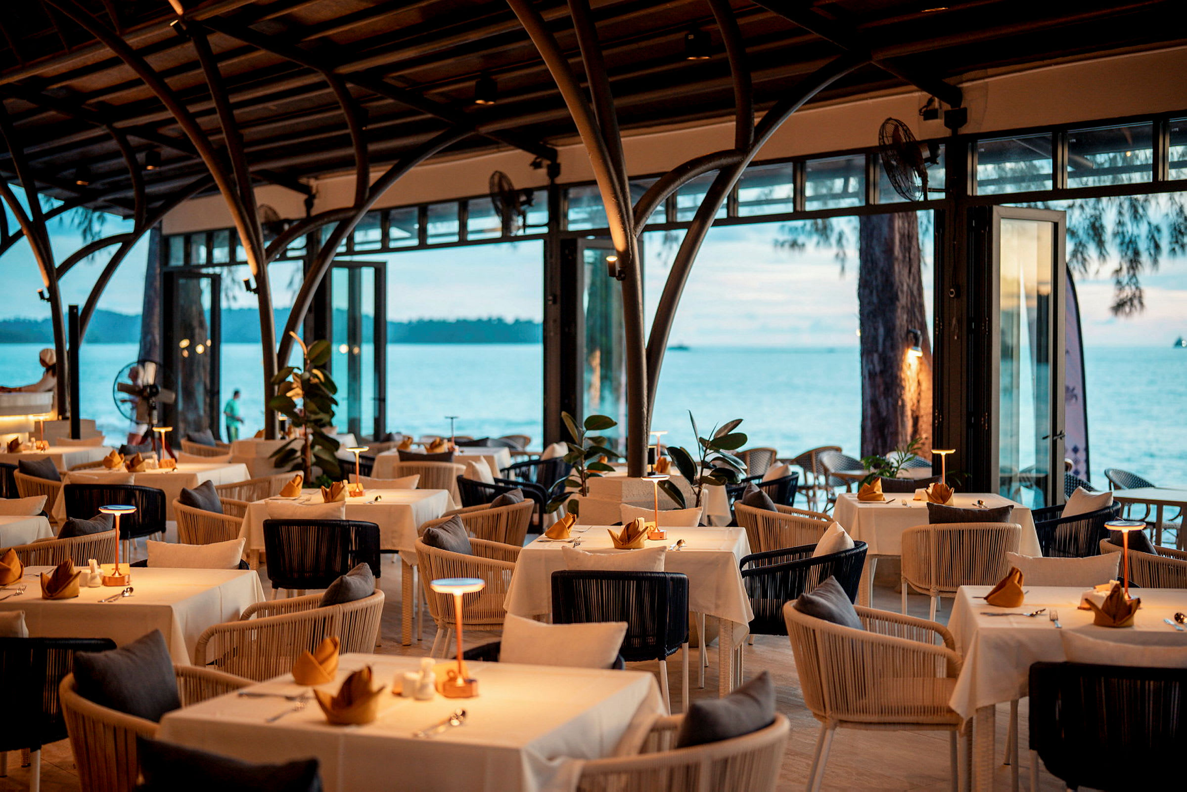 En elegant restaurant med dækkede borde og havudsigt. (AI-genereret tekst)