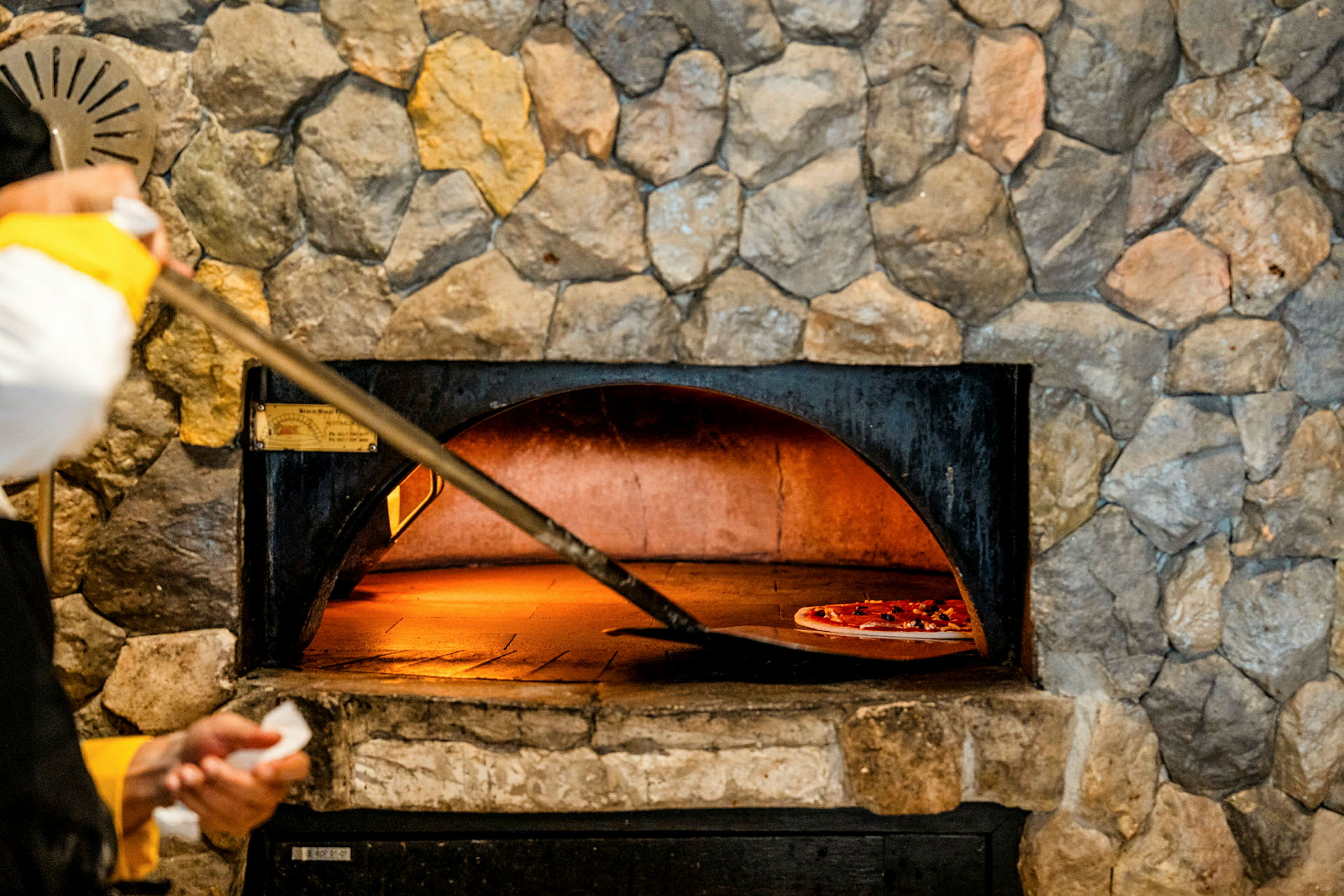 En stenovn med en pizza, der bages på en bageplade. (AI-genereret tekst)