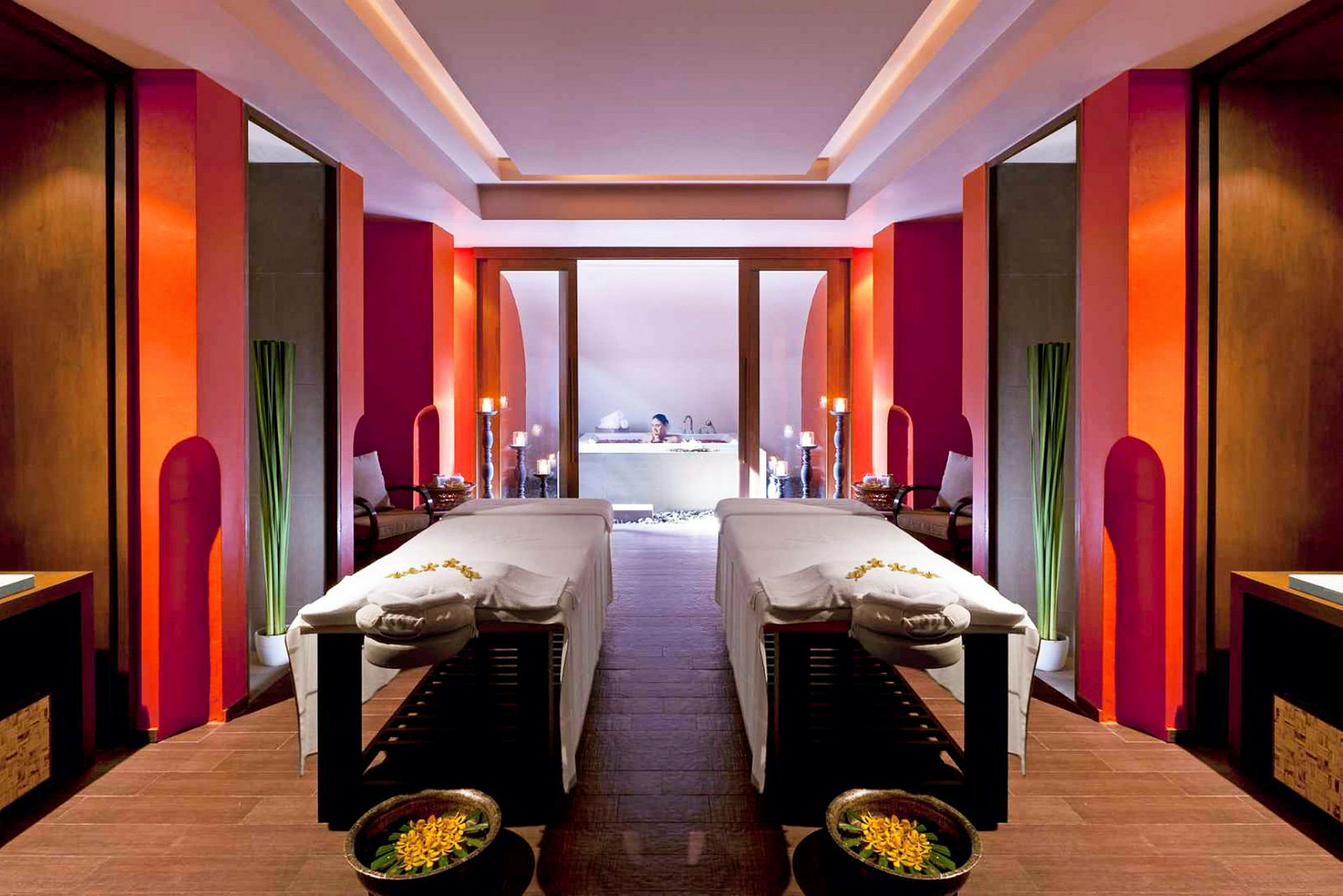 Et spa-rum med to massageborde, dekoreret med blomster og omgivet af moderne, varme farver. (AI-genereret tekst)