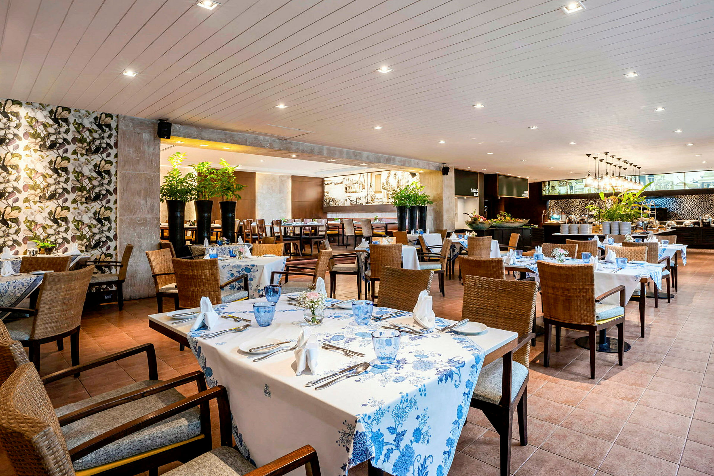 En restaurant med dækkede borde, blomstrede dekorationer og moderne møbler. (AI-genereret tekst)