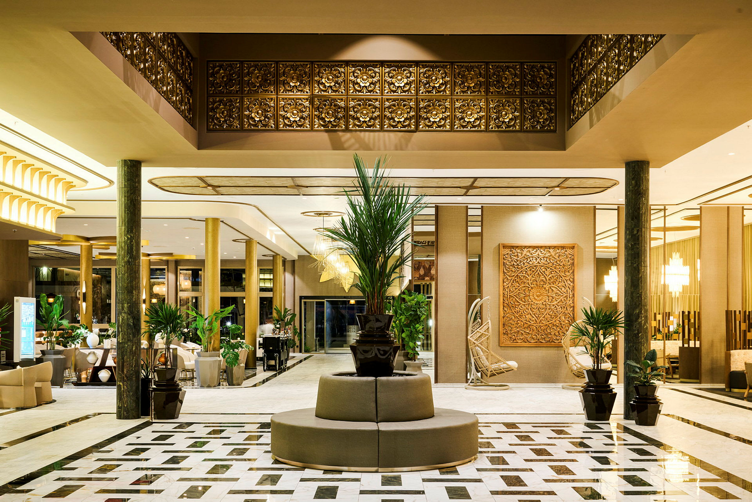 En elegant hotellobby med marmorgulve, dekorationer i guld og træ samt planter placeret rundt omkring. (AI-genereret tekst)
