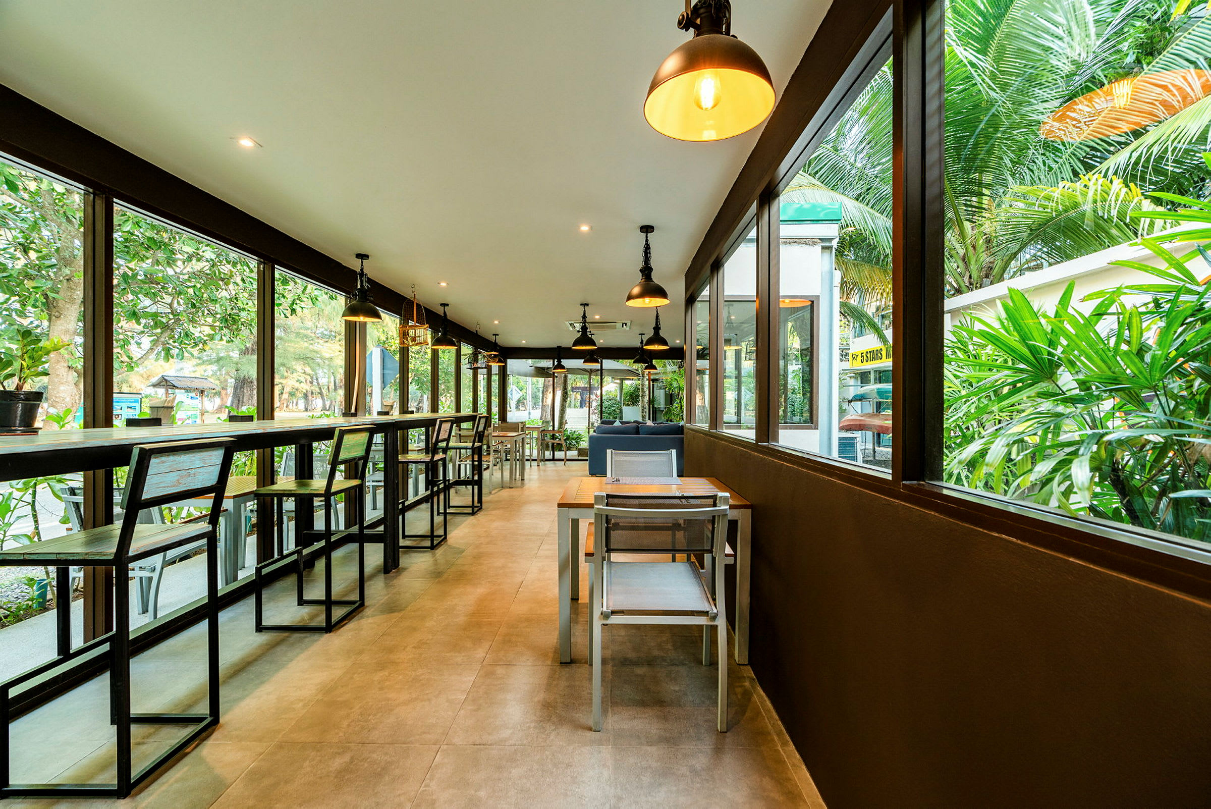 En moderne restaurant med store glasvinduer og udsigt til grønne omgivelser. (AI-genereret tekst)