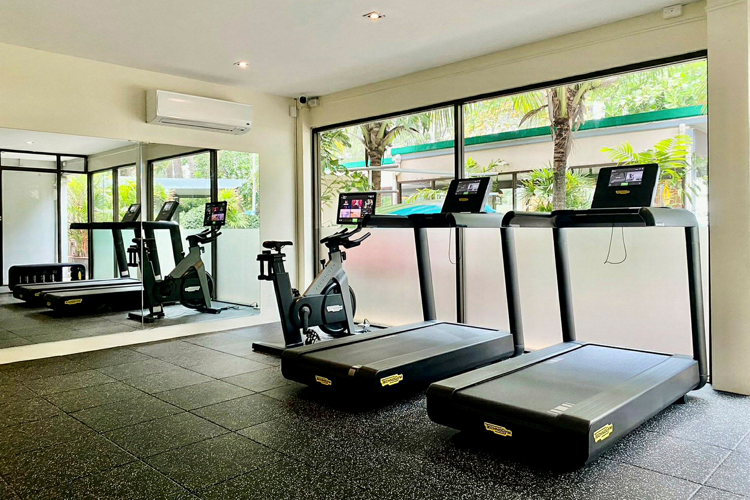 Billede af et fitnesscenter med løbebånd og motionscykel foran store vinduer. (AI-genereret tekst)