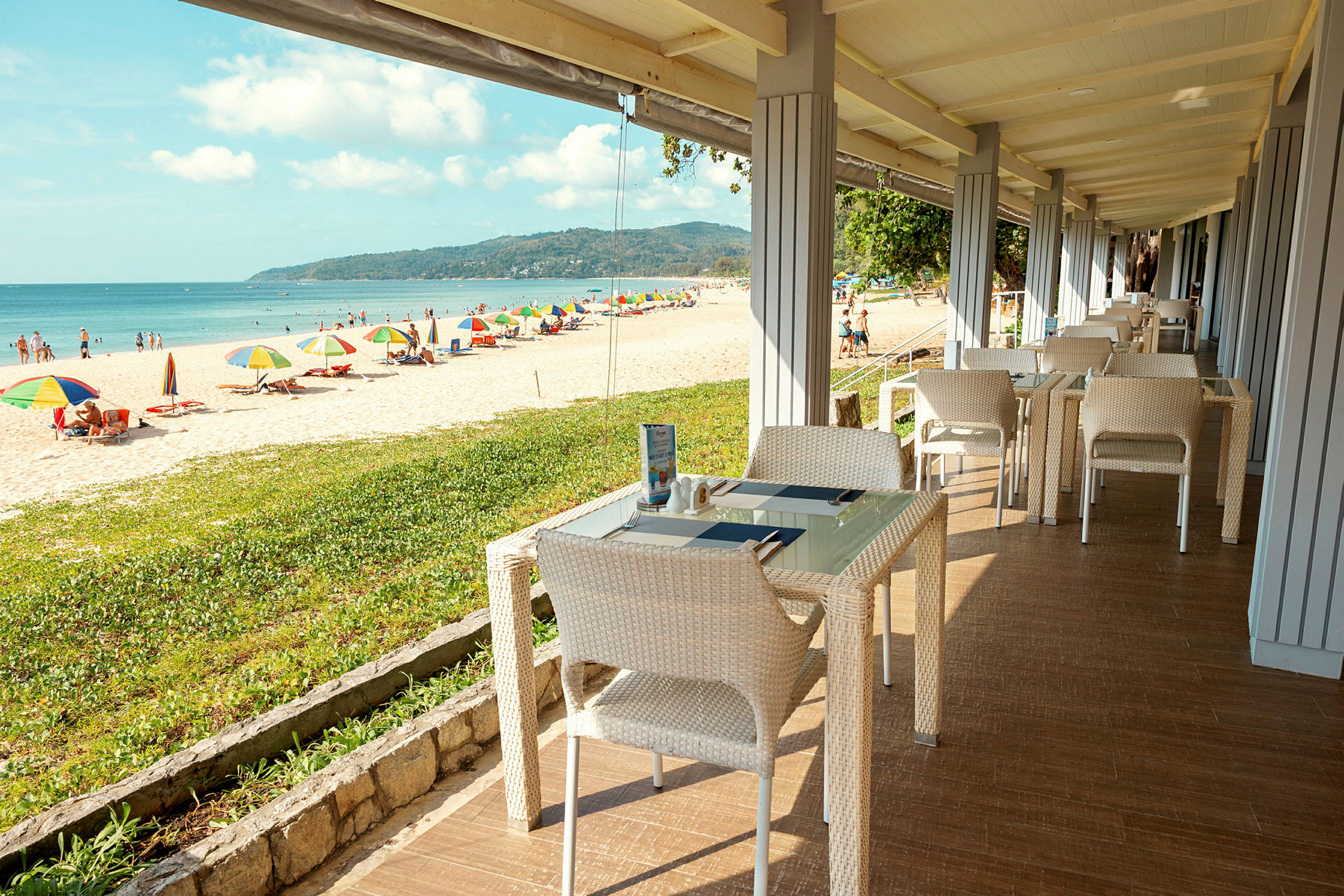 Restaurant med havudsigt tæt på en strand med parasoller. (AI-genereret tekst)