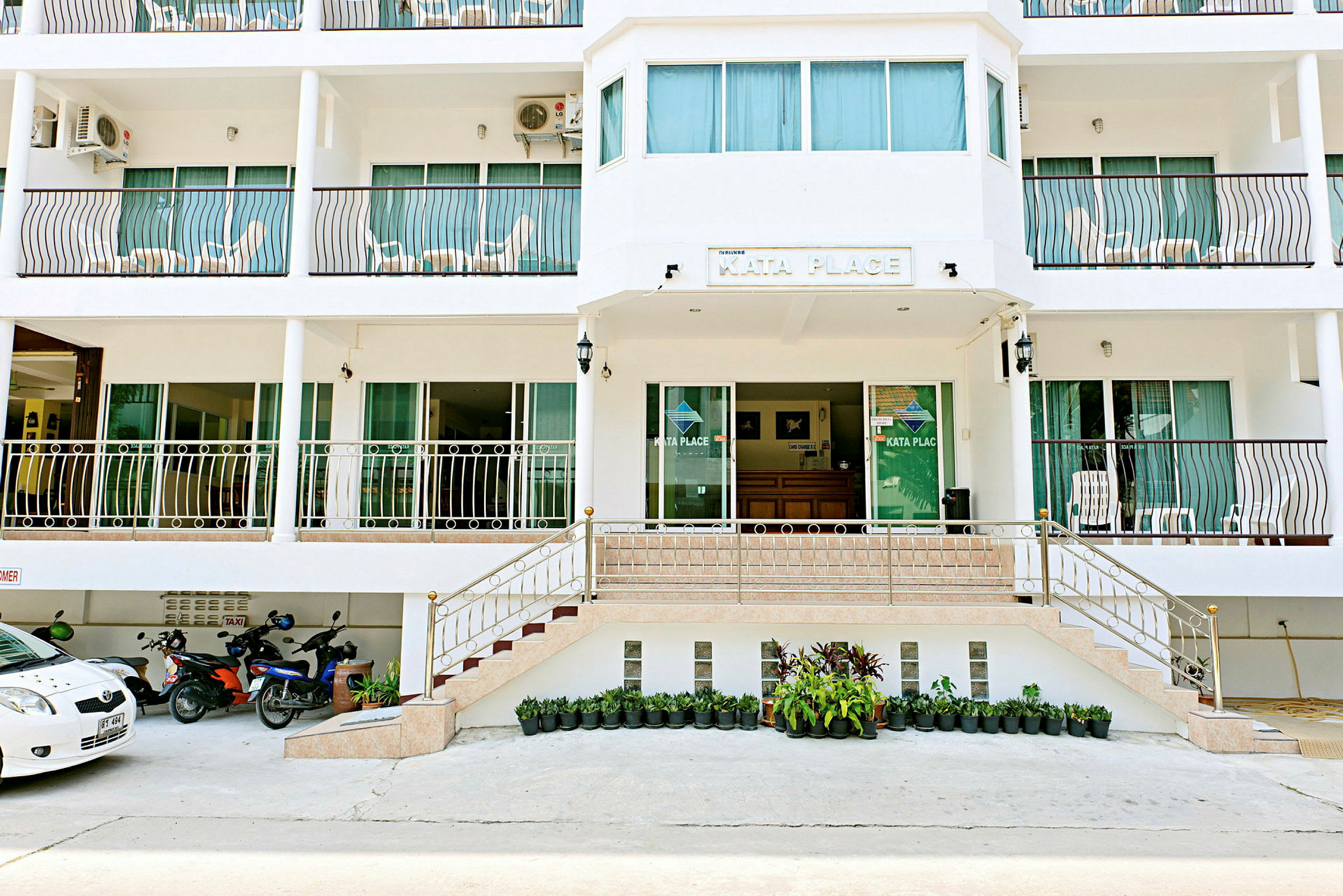 Hotellets facade med en indgang og flere altaner. (AI-genereret tekst)