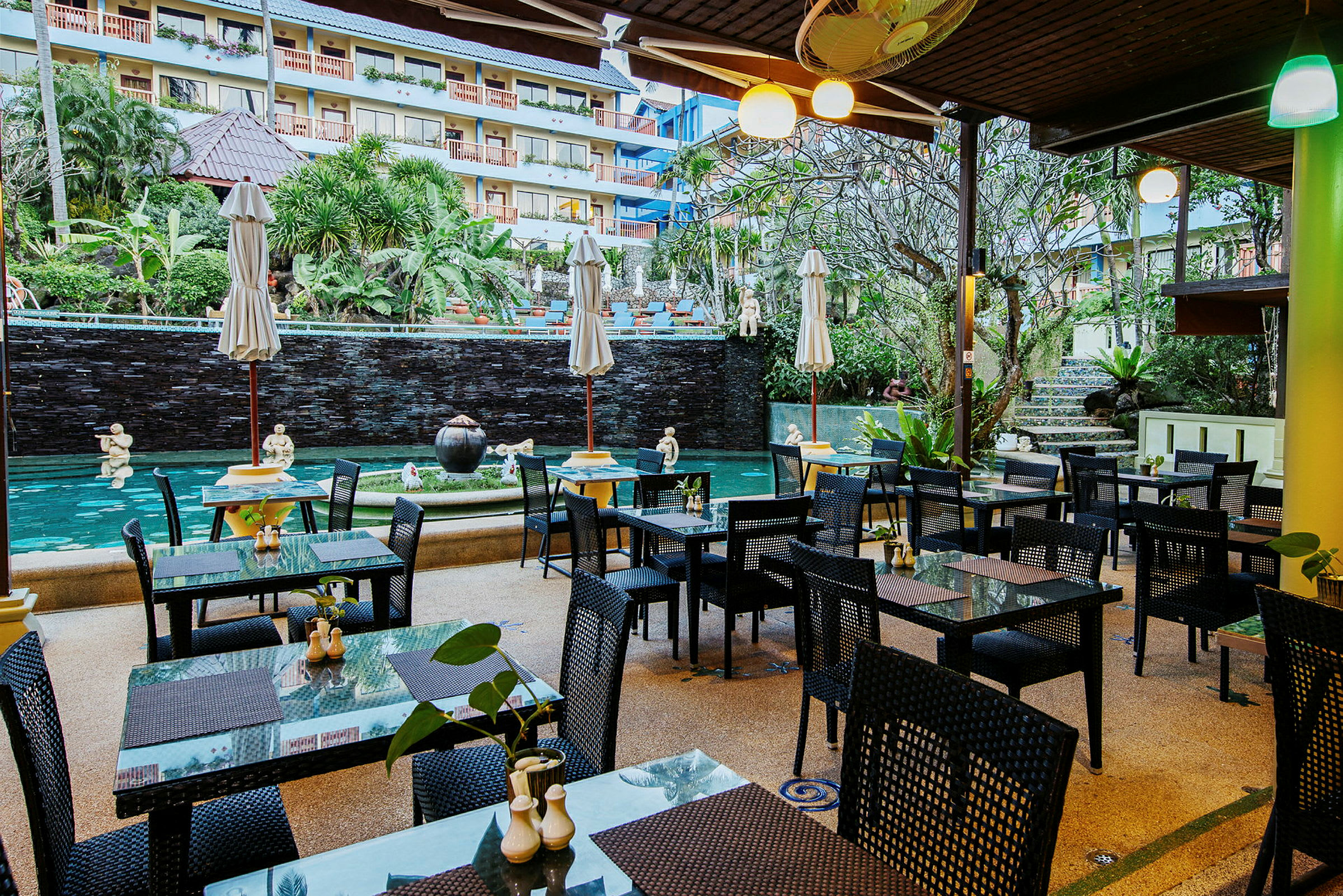En åben restaurant med borde og stole ved en smuk springvand og pool. (AI-genereret tekst)