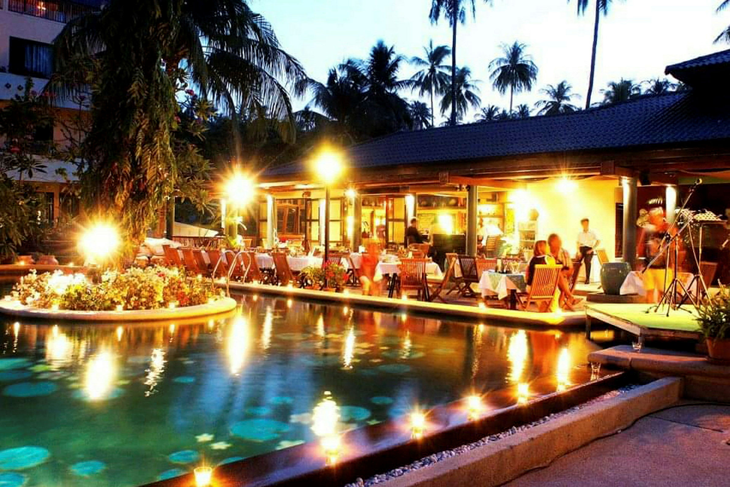 Udendørsrestaurant med belysning ved en pool om aftenen (AI-genereret tekst)