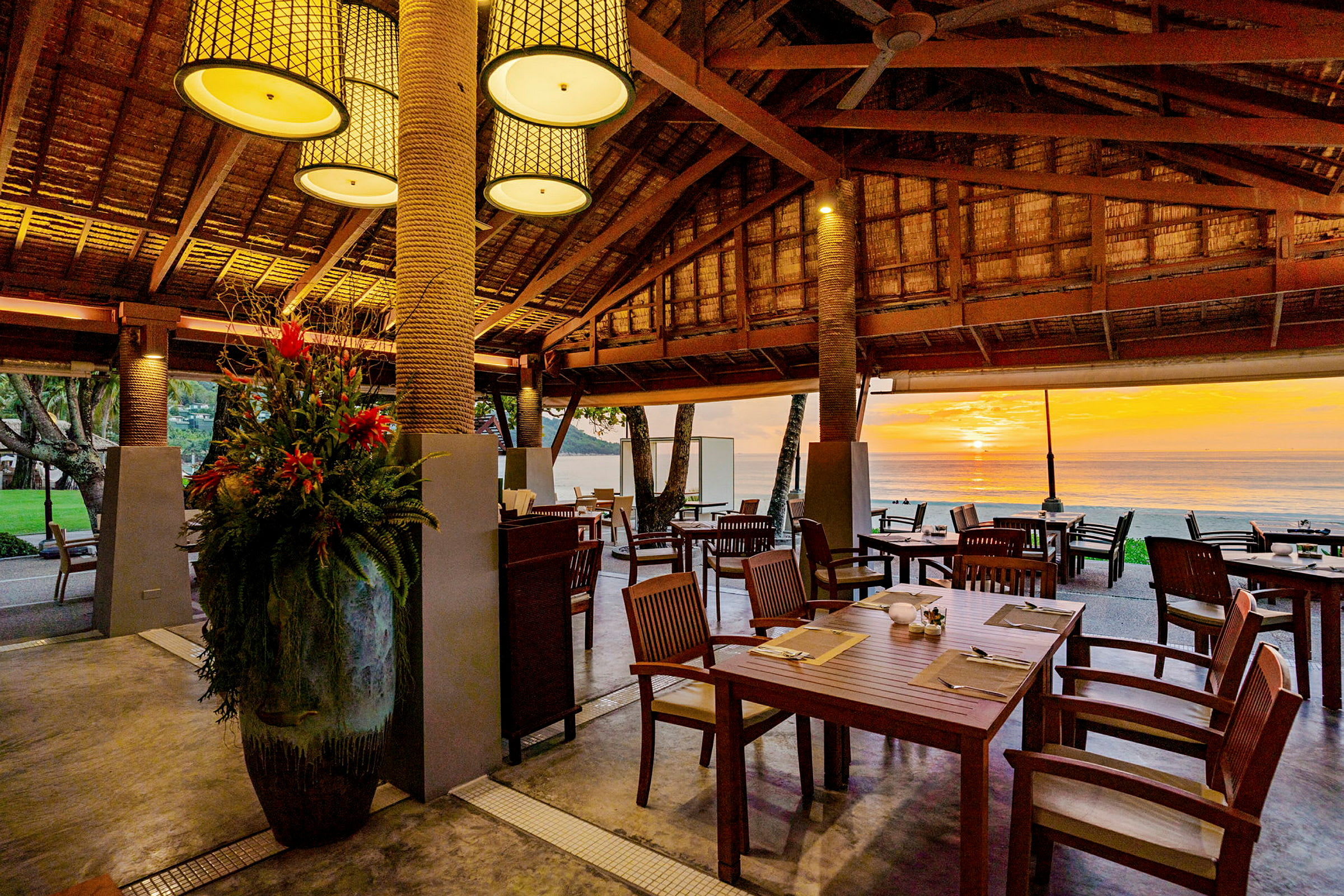 Restaurant med træinteriør og havudsigt ved solnedgang. (AI-genereret tekst)