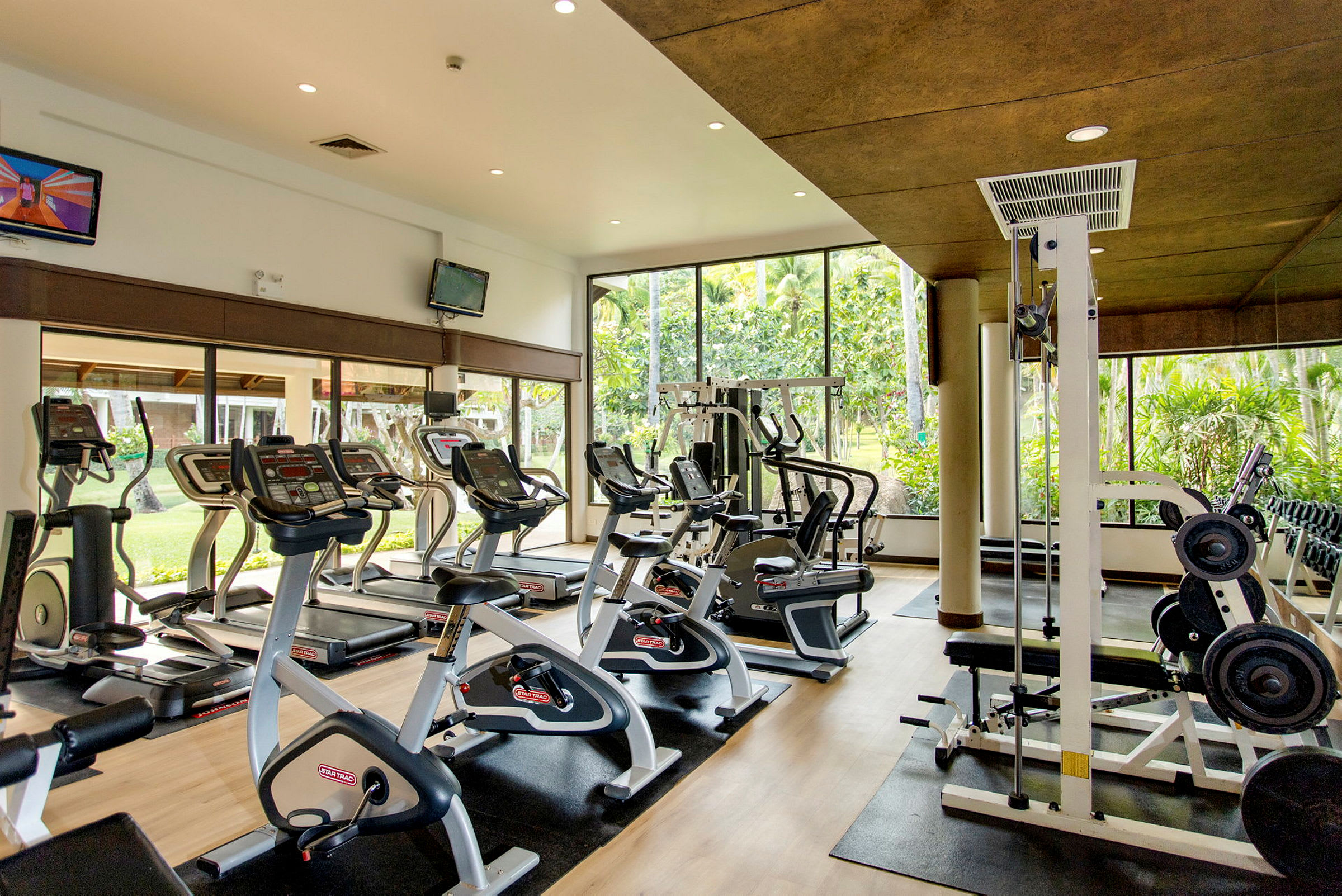 Fitnesscenter med træningsmaskiner og store vinduer. (AI-genereret tekst)