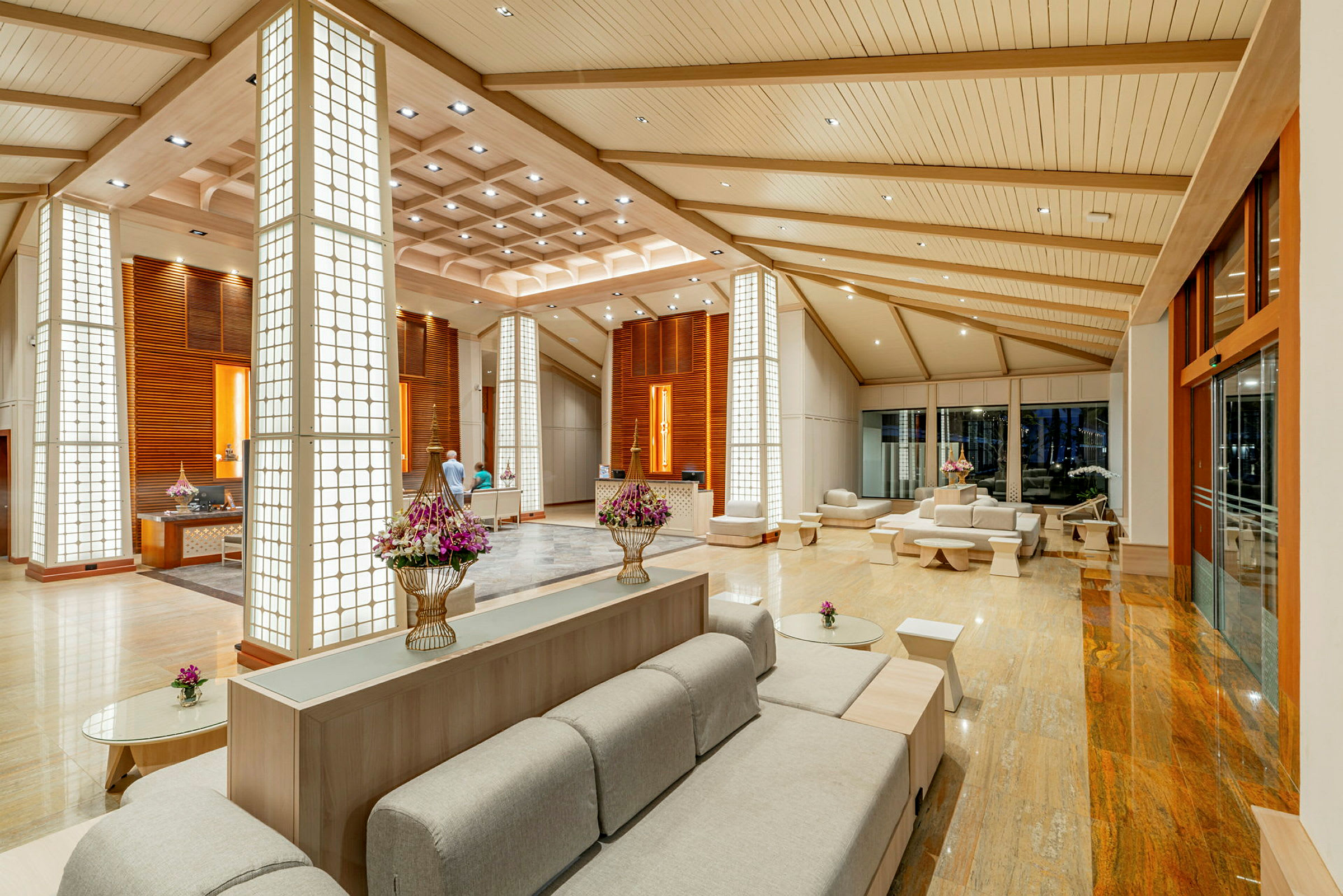 Moderne hotellobby med siddepladser, dekorative søjler og blomster. (AI-genereret tekst)