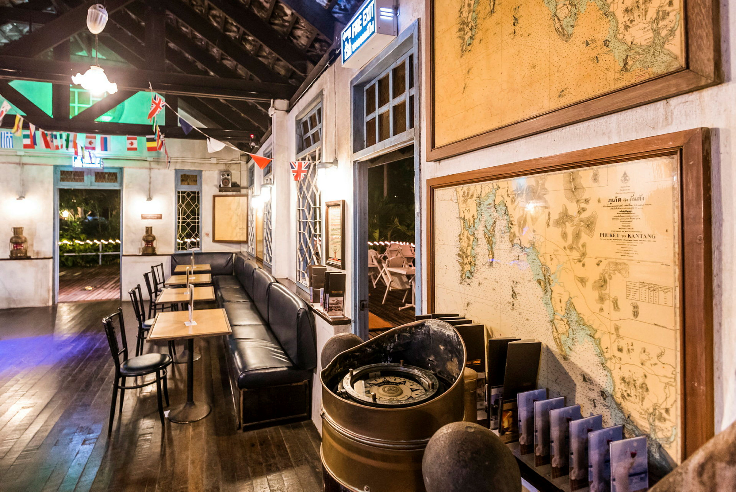 Interiør af en café med borde og stole, dekoreret med kort og flag. (AI-genereret tekst)