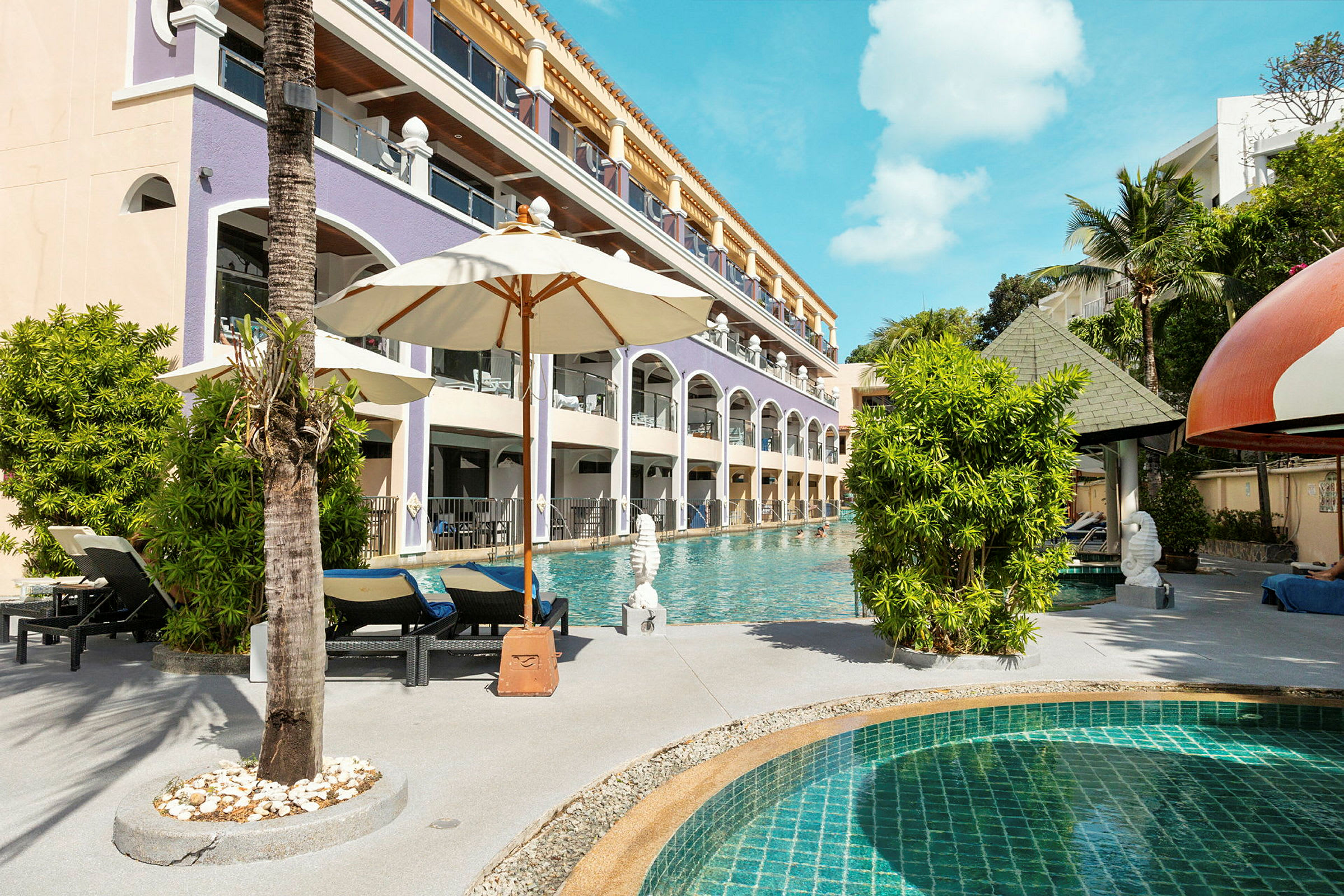 En pool med liggestole og parasoller ved siden af en hotelbygning. (AI-genereret tekst)