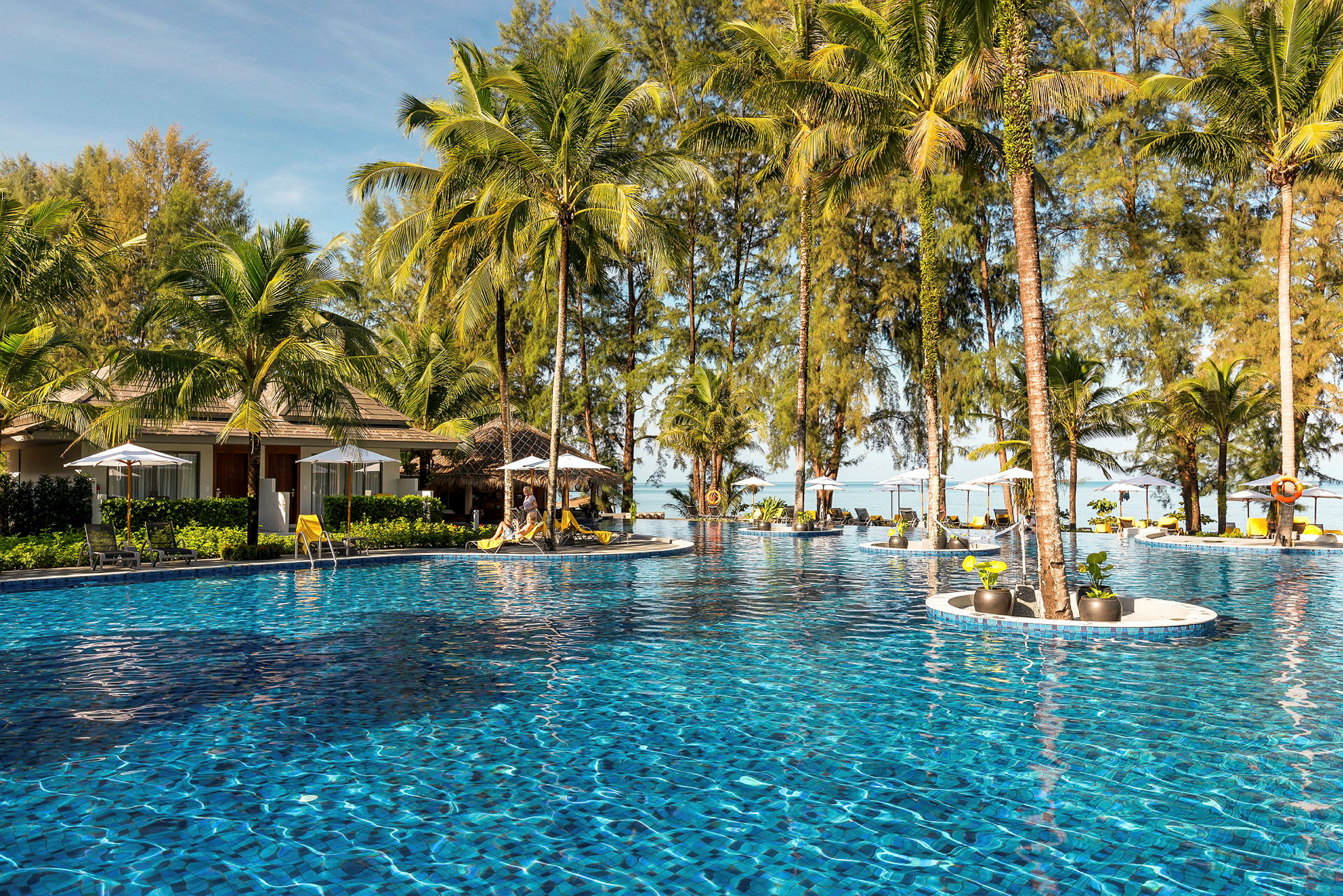 En swimmingpool omgivet af palmer og liggestole. (AI-genereret tekst)