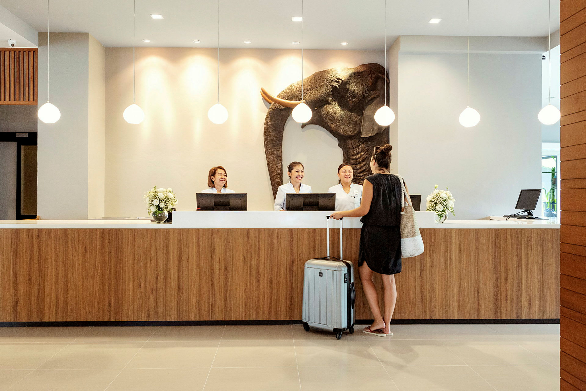En kvinde står ved en hotelreception med en kuffert. (AI-genereret tekst)