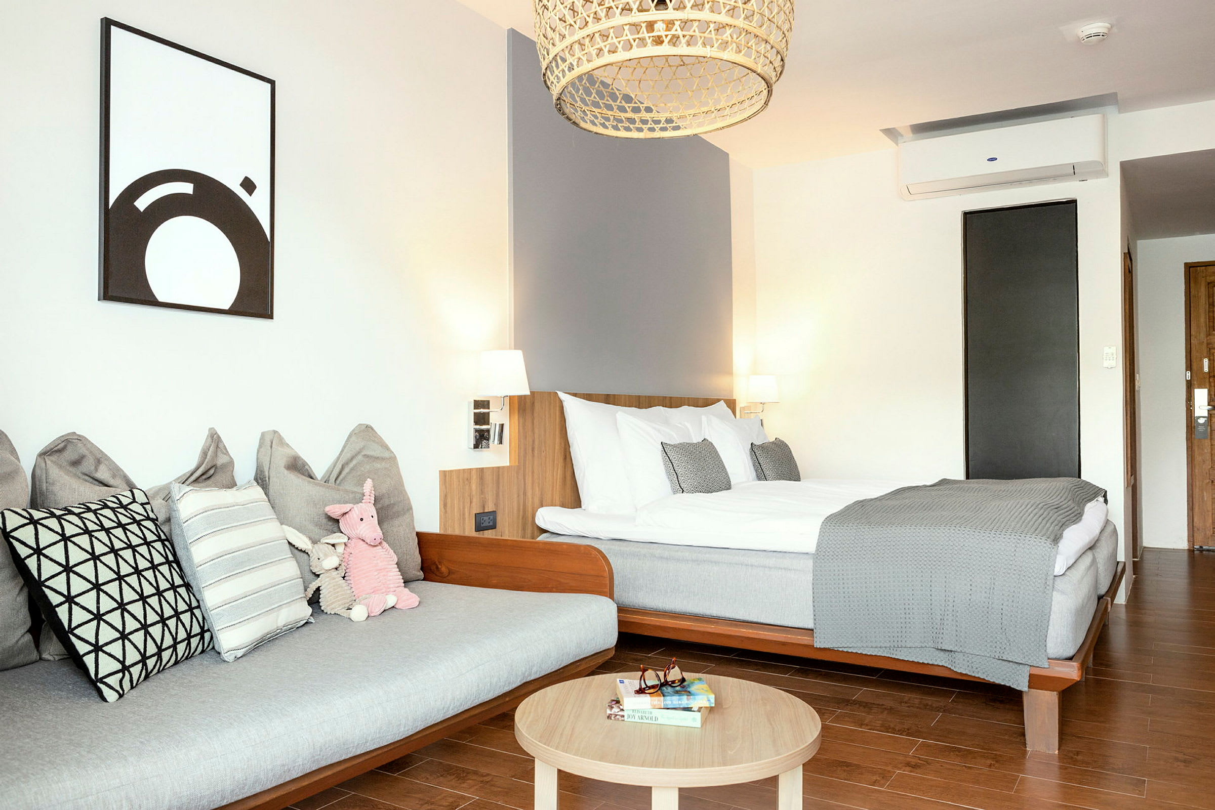 Et moderne hotelværelse med en seng, en sofa og et træbord. (AI-genereret tekst)