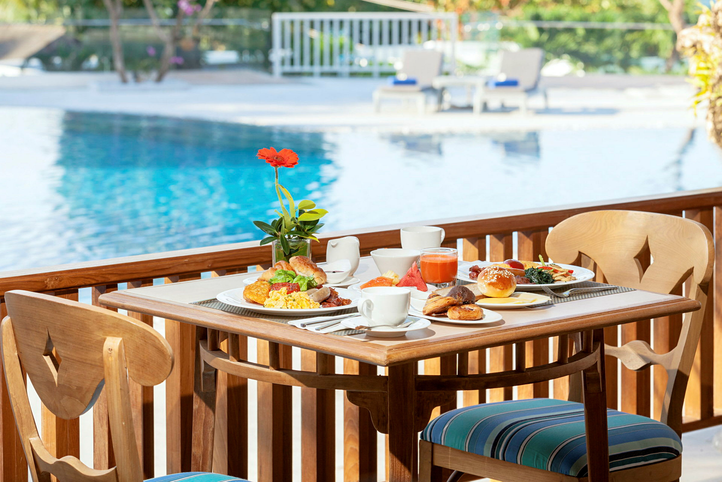 En morgenmad serveret på et bord ved siden af en swimmingpool. (AI-genereret tekst)