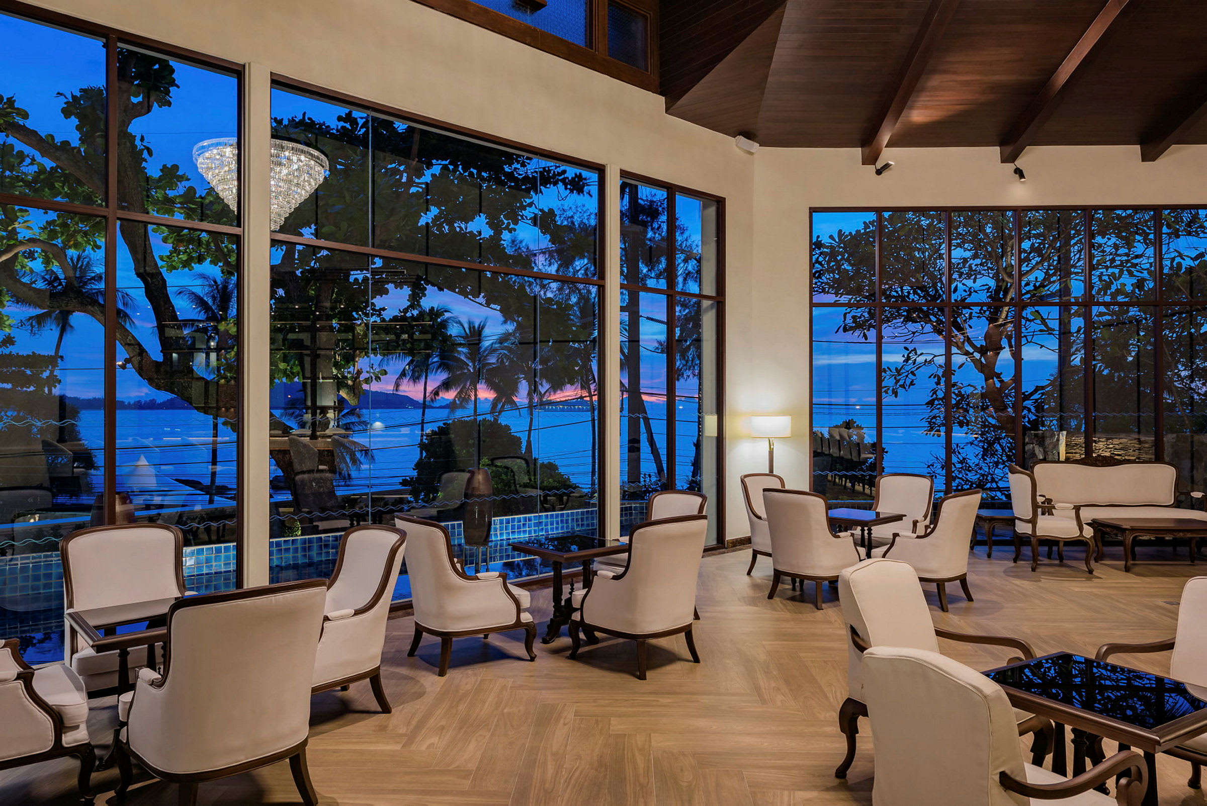 En elegant hotellobby med hvide lænestole og store vinduer med udsigt til havet. (AI-genereret tekst)