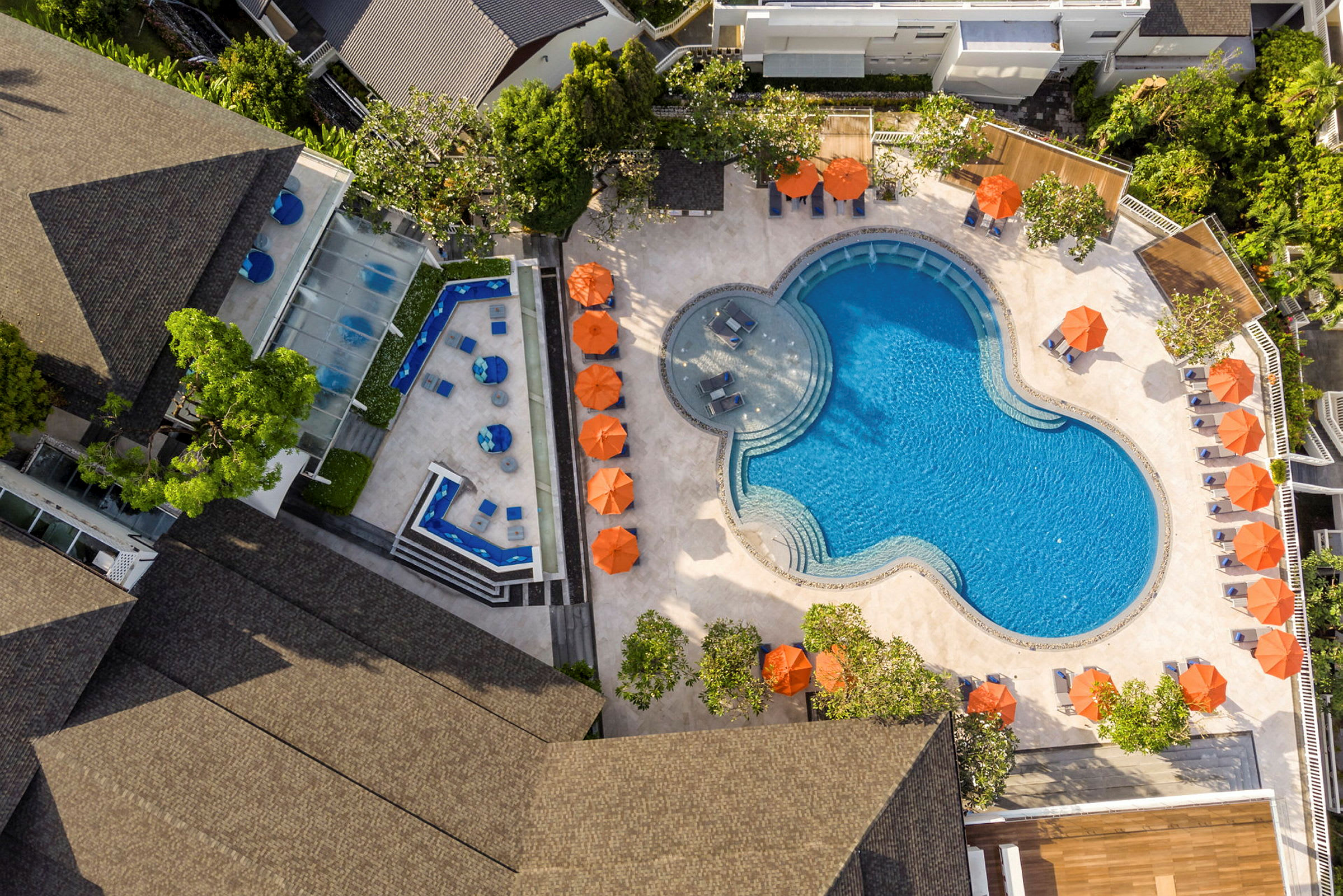 Luftfoto af swimmingpool og terrasse med liggestole og parasoller. (AI-genereret tekst)