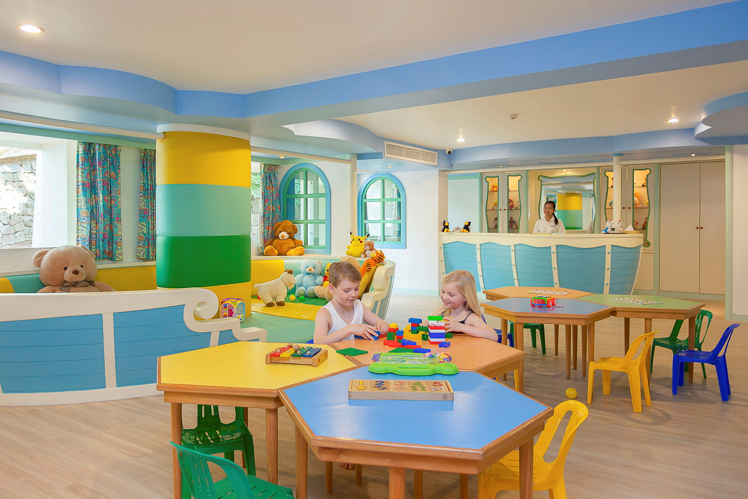 Et farverigt legeområde med legetøj og små borde og stole. (AI-genereret tekst)