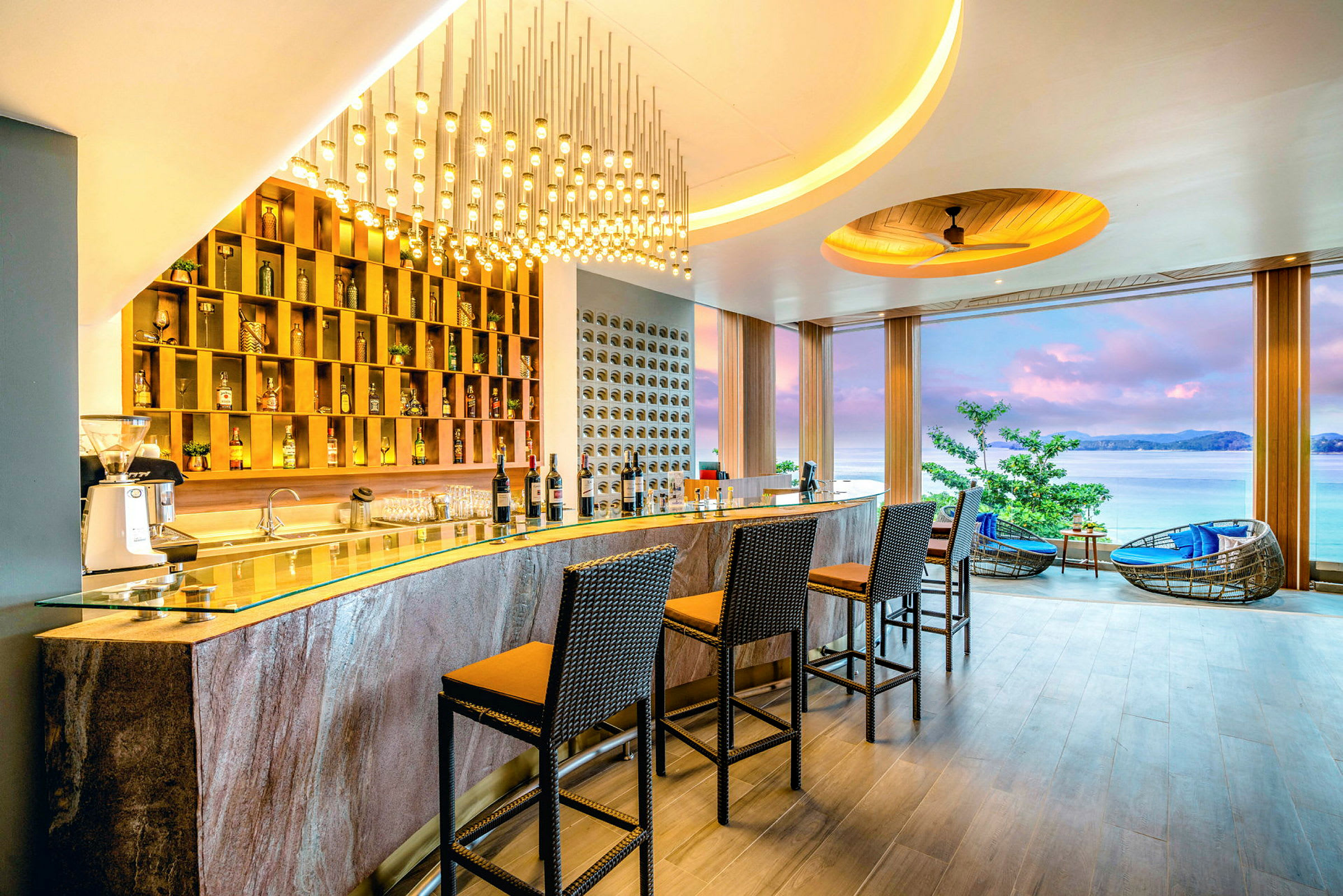 En hotelbar med stole og et panoramavindue med udsigt over havet. (AI-genereret tekst)