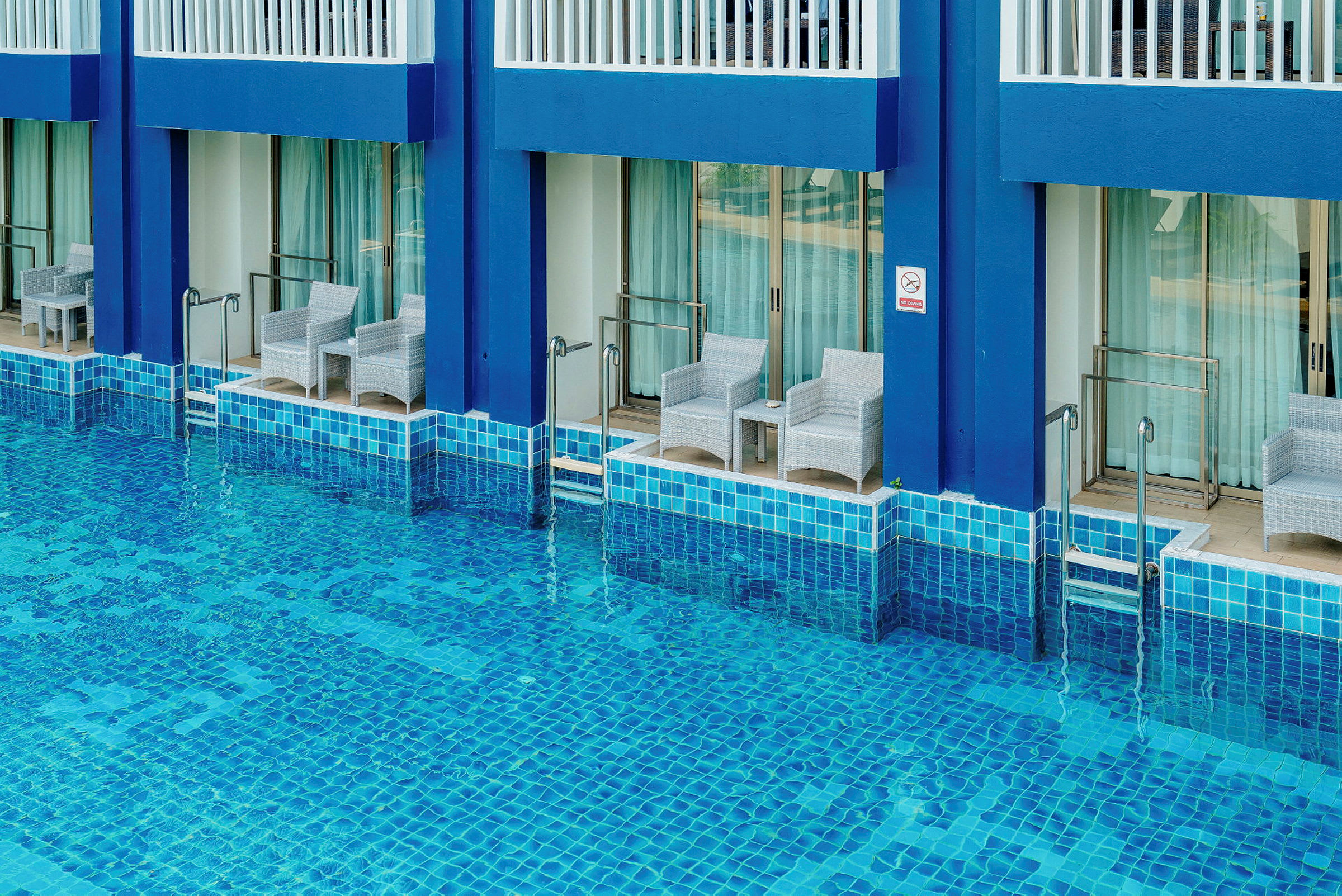 Flere hotelværelser med terrasser direkte ved en pool. (AI-genereret tekst)