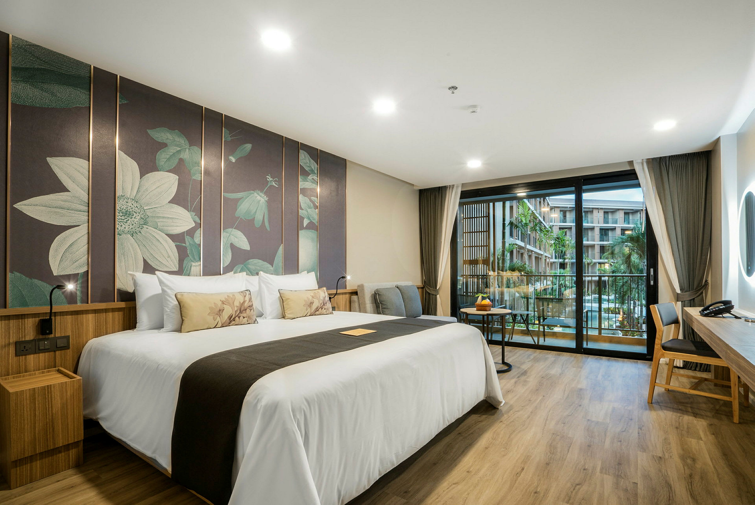 Hotelværelse med en stor dobbeltseng, moderne indretning og en balkon med udsigt over en pool og bygninger. (AI-genereret tekst)