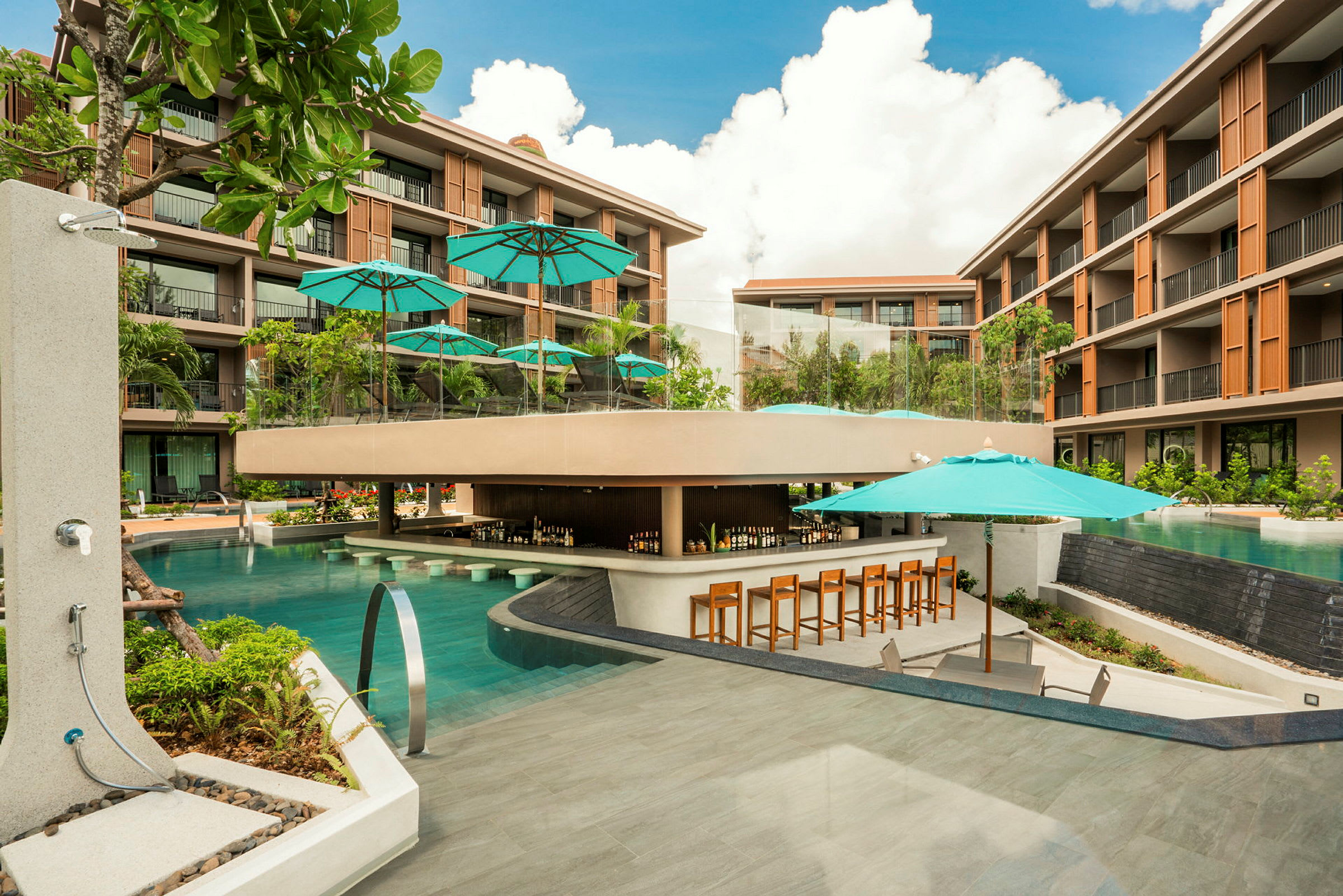 Et moderne hotelkompleks med en stor pool, der omgiver en poolbar med parasoller og stole placeret rundt omkring. (AI-genereret tekst)