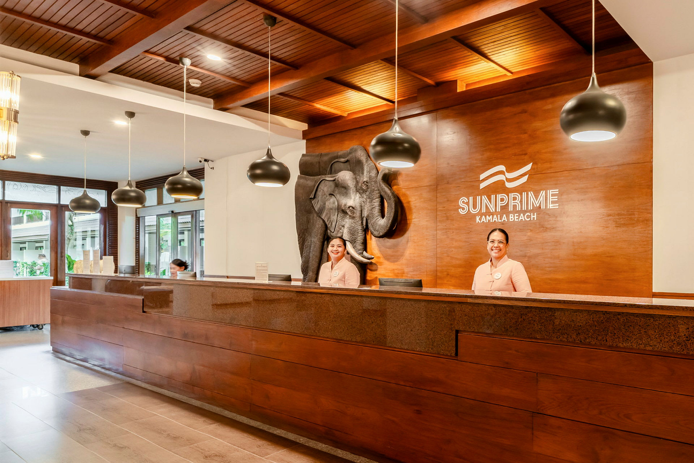 Receptionen på Sunprime Kamala Beach med træinteriør og dekorativt elefantmotiv. (AI-genereret tekst)