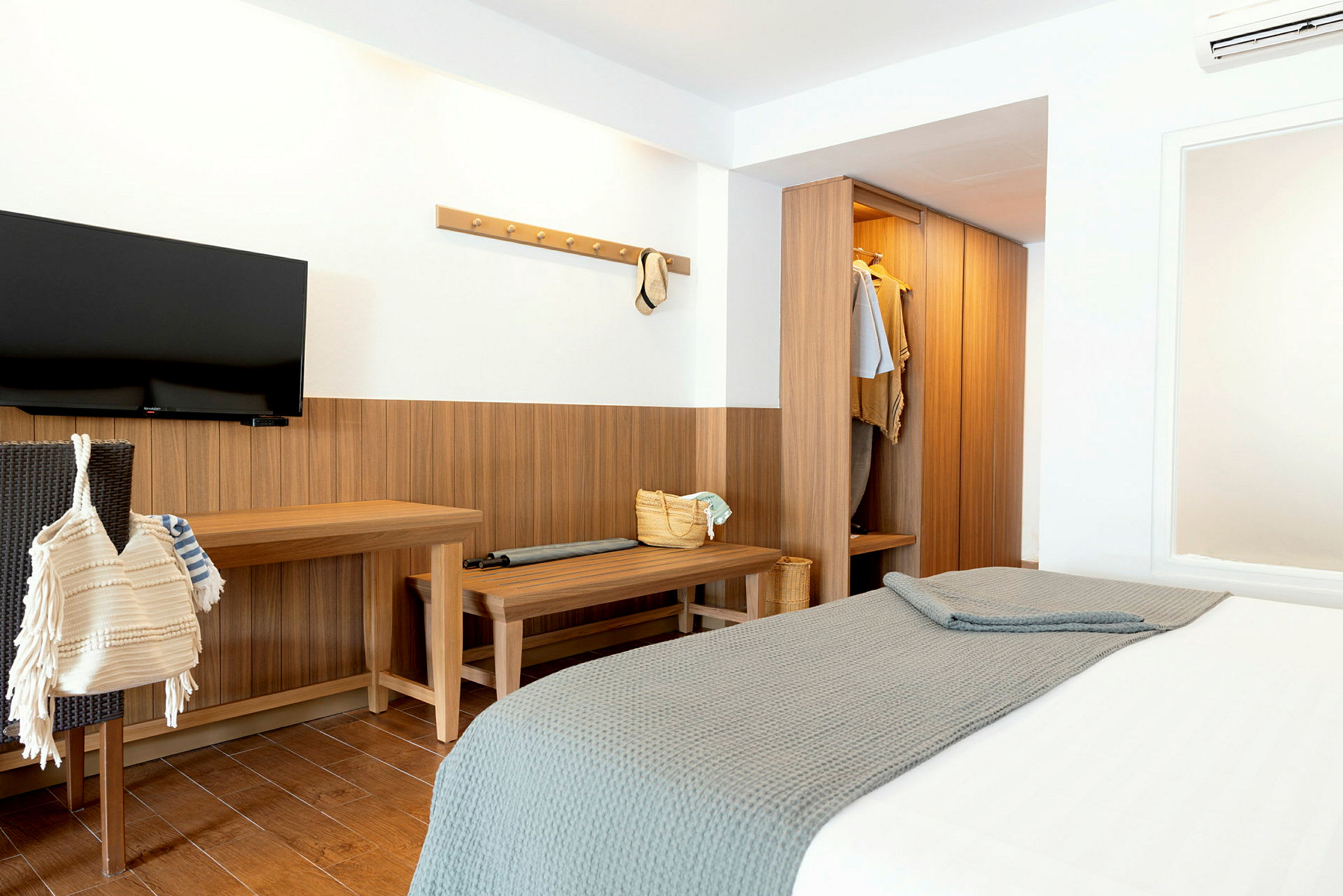 Et hotelværelse med en seng, garderobe og et TV på væggen. (AI-genereret tekst)