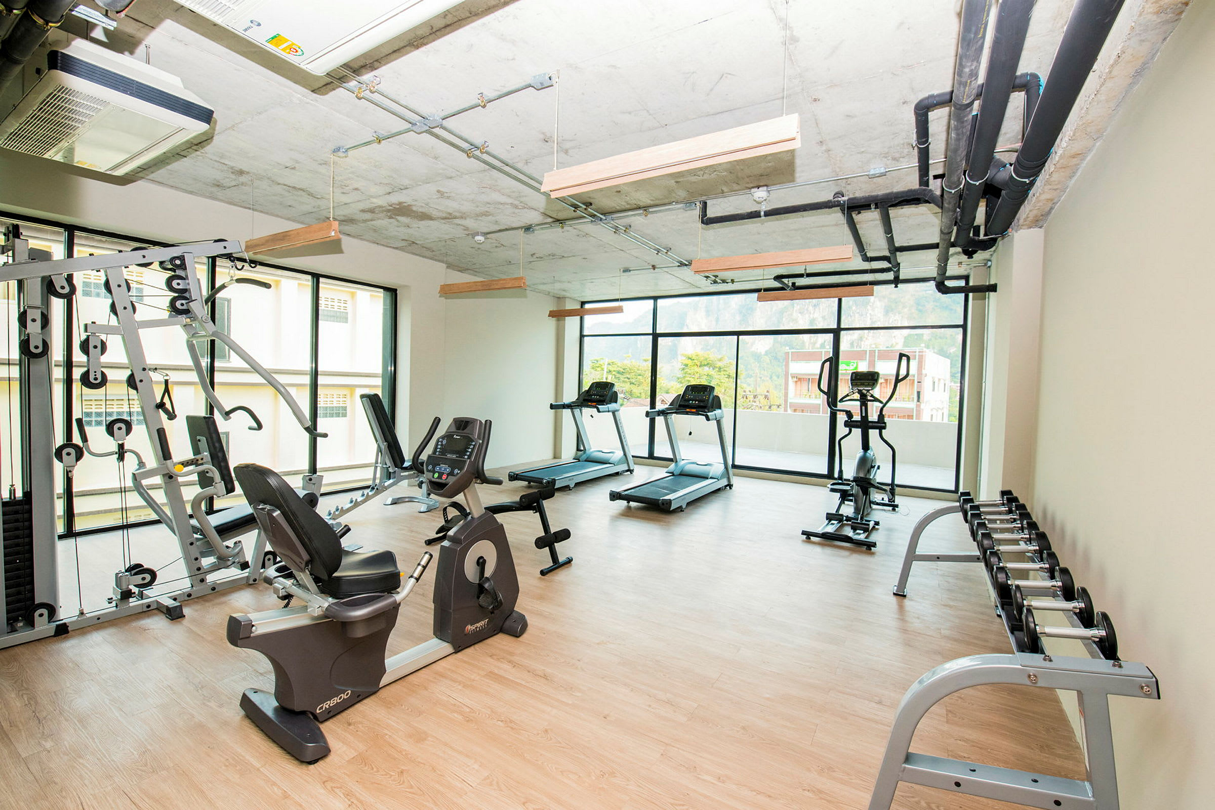 Et lyst fitnesscenter med træningsmaskiner, vægte og løbebånd. (AI-genereret tekst)