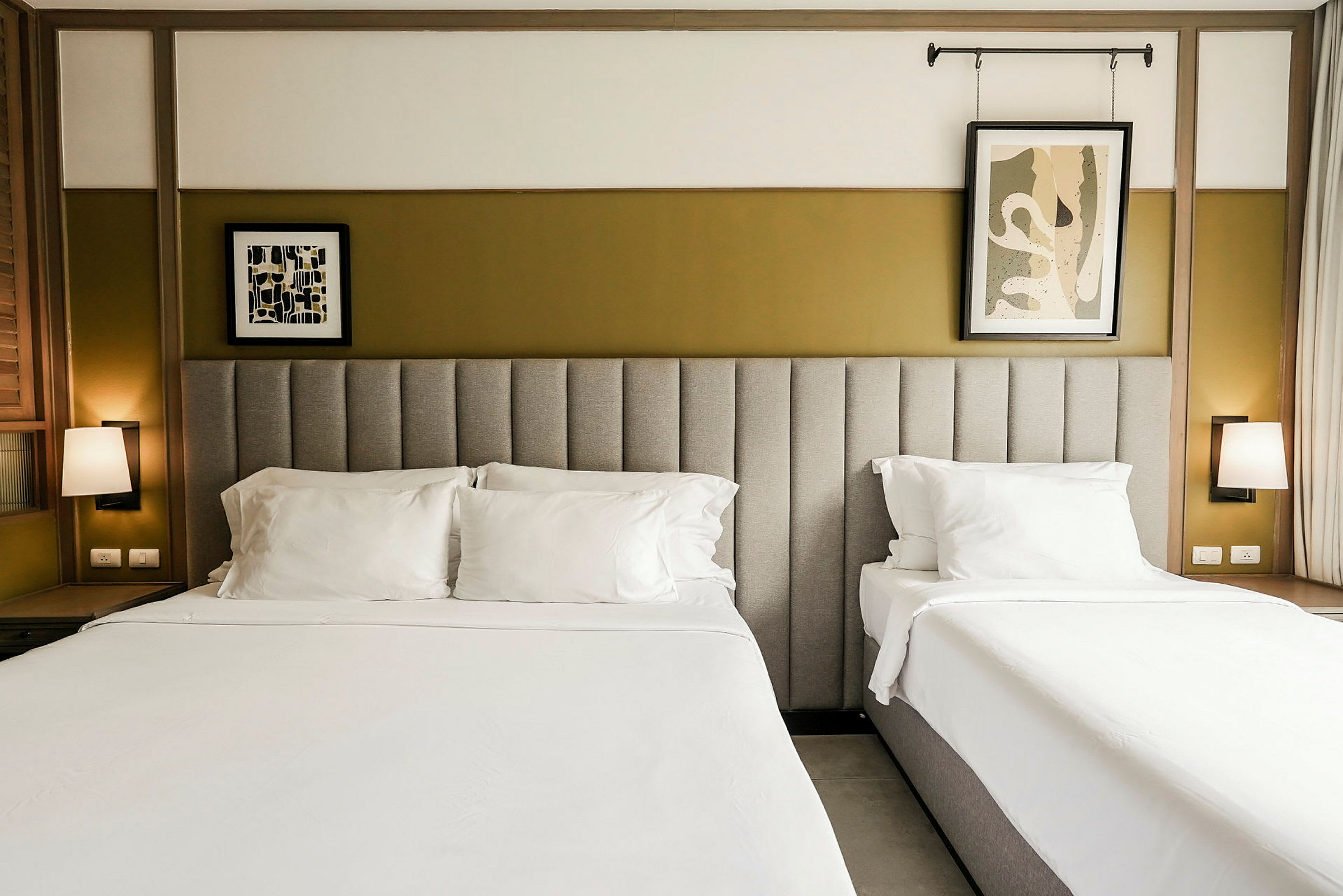 To senge med hvidt sengelinned og polstrede sengegavle, placeret i et moderne rum med vægdekorationer. (AI-genereret tekst)