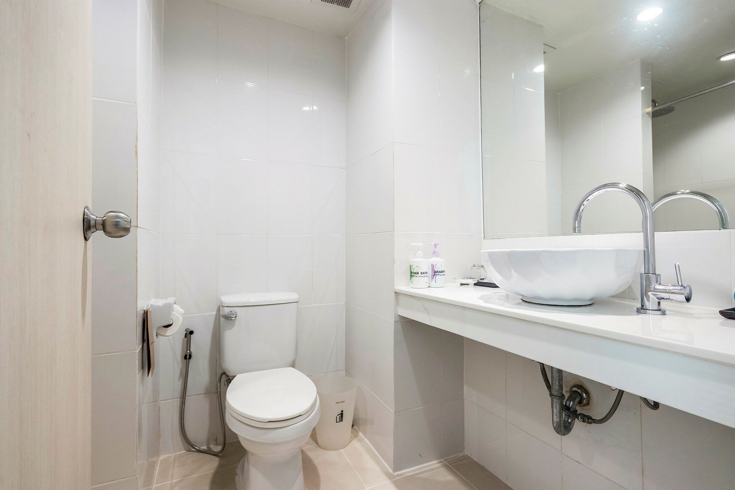 Et badeværelse med toilet, håndvask og spejl. (AI-genereret tekst)