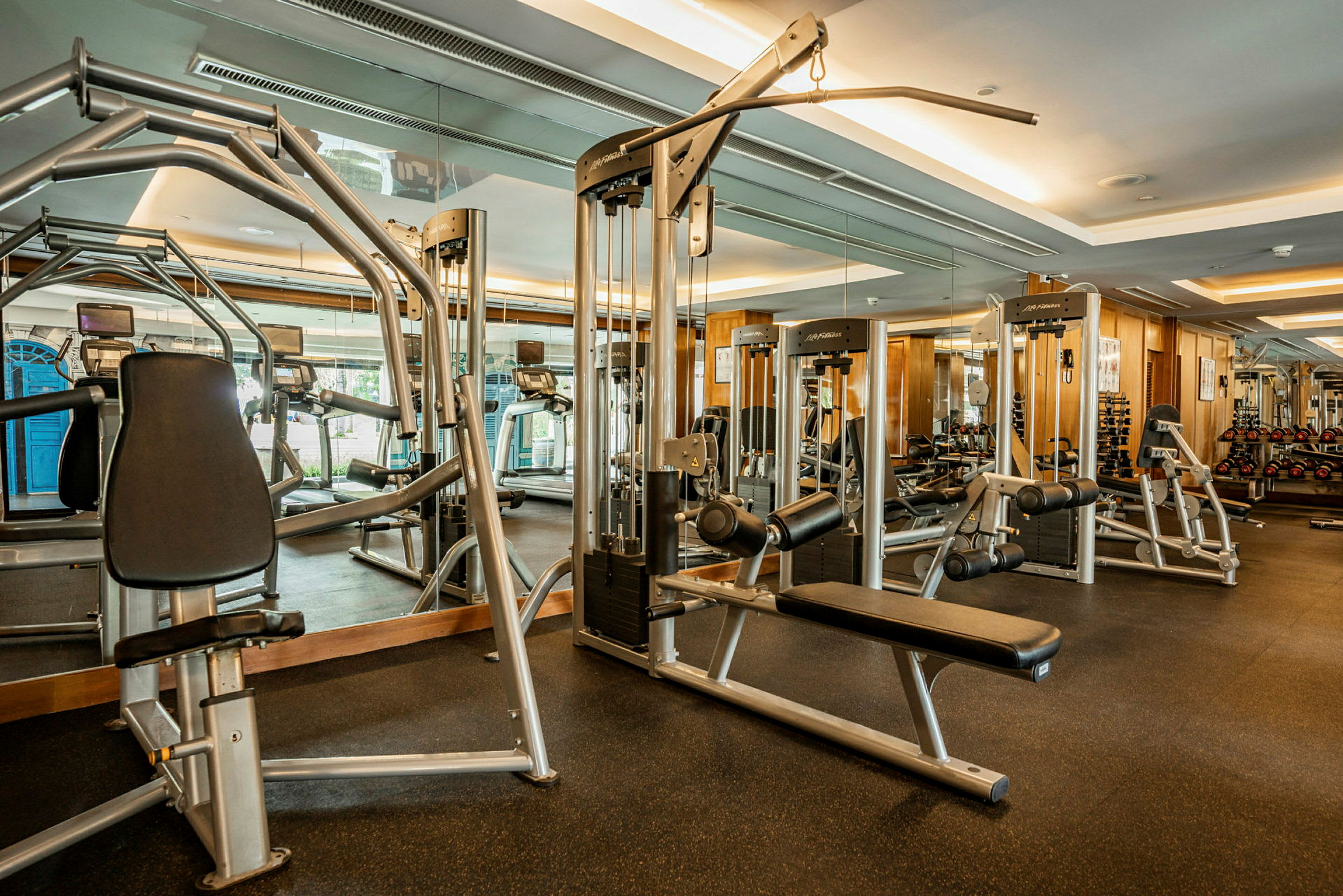 Et fitnesscenter med træningsmaskiner og vægge med spejle. (AI-genereret tekst)