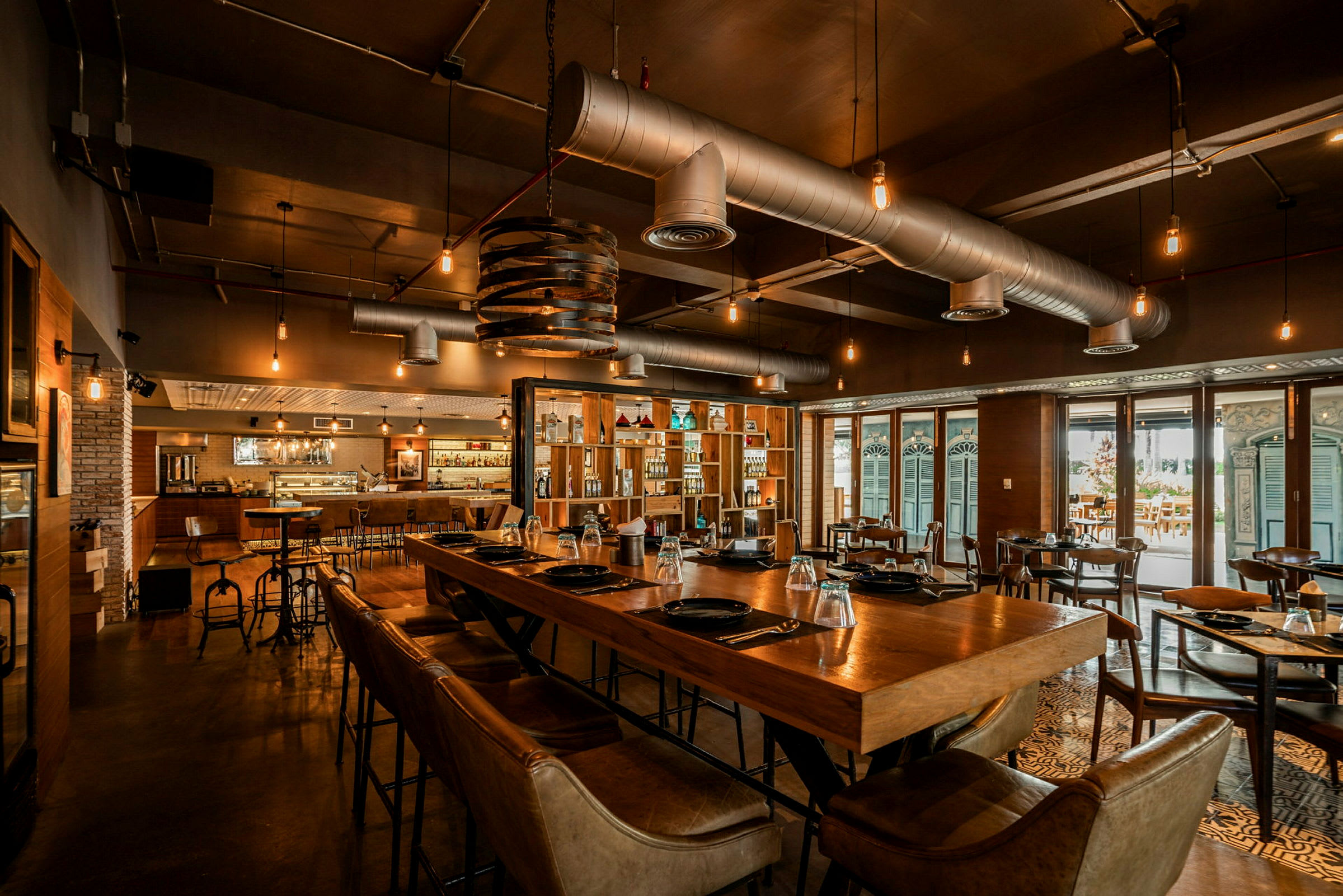 Restaurant med moderne indretning, træborde og stole, belyst med hængende lamper. (AI-genereret tekst)