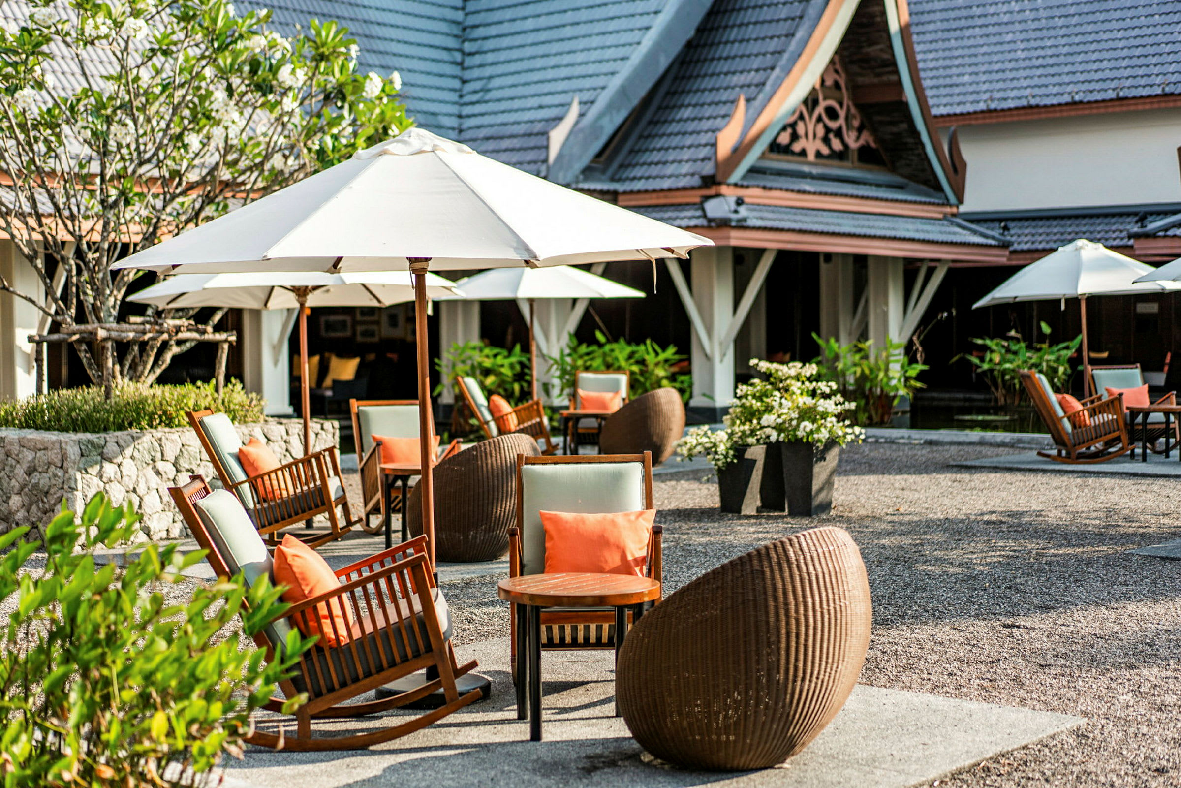 En terrasse ved en bygning med stole, borde og parasoller. (AI-genereret tekst)