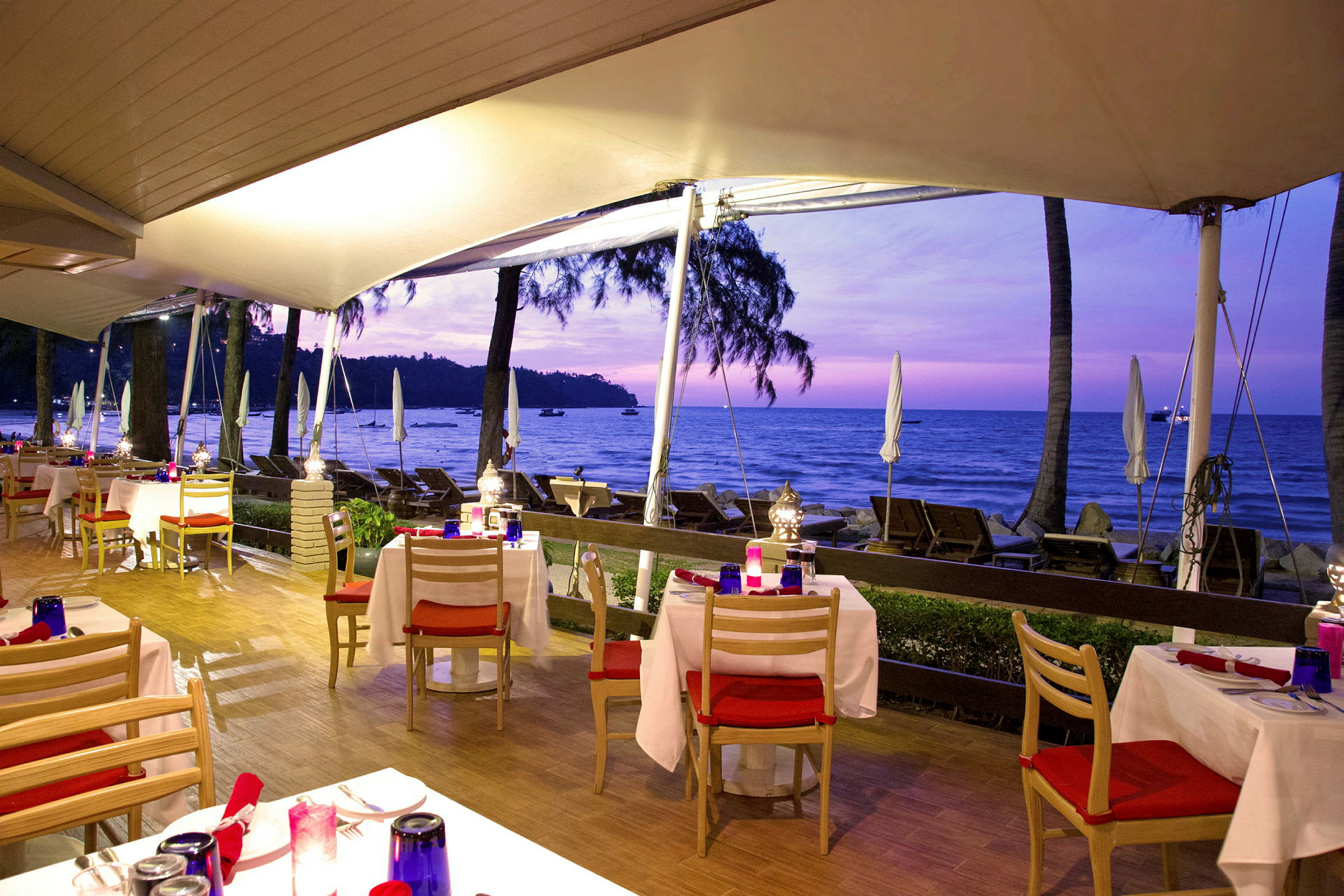 Restaurant med udendørs servering ved stranden i solnedgangen. (AI-genereret tekst)