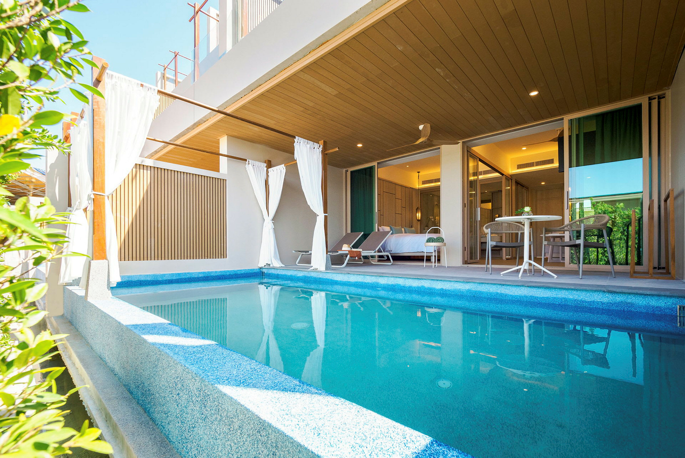 Privat pool med liggestole og siddeområde foran et soveværelse. (AI-genereret tekst)