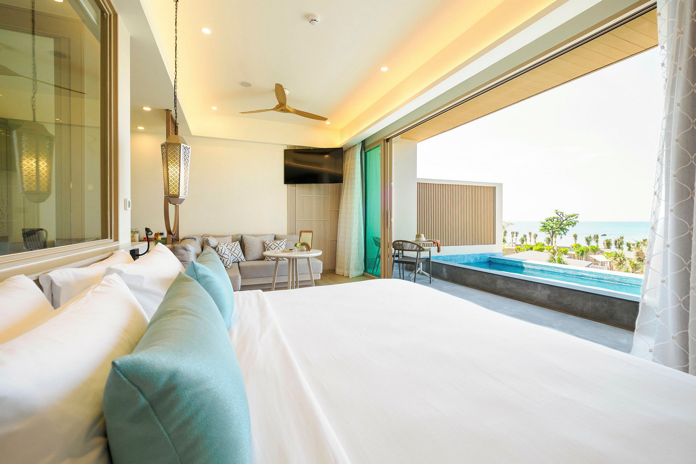 Hotelværelse med seng, opholdsområde og adgang til terrasse med lille pool og havudsigt. (AI-genereret tekst)