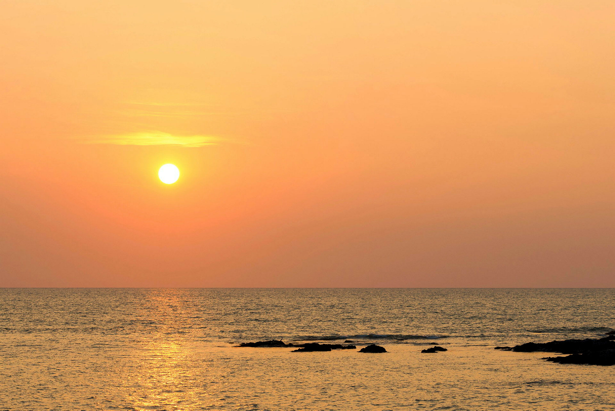 Solnedgang over havet med klipper i vandet. (AI-genereret tekst)