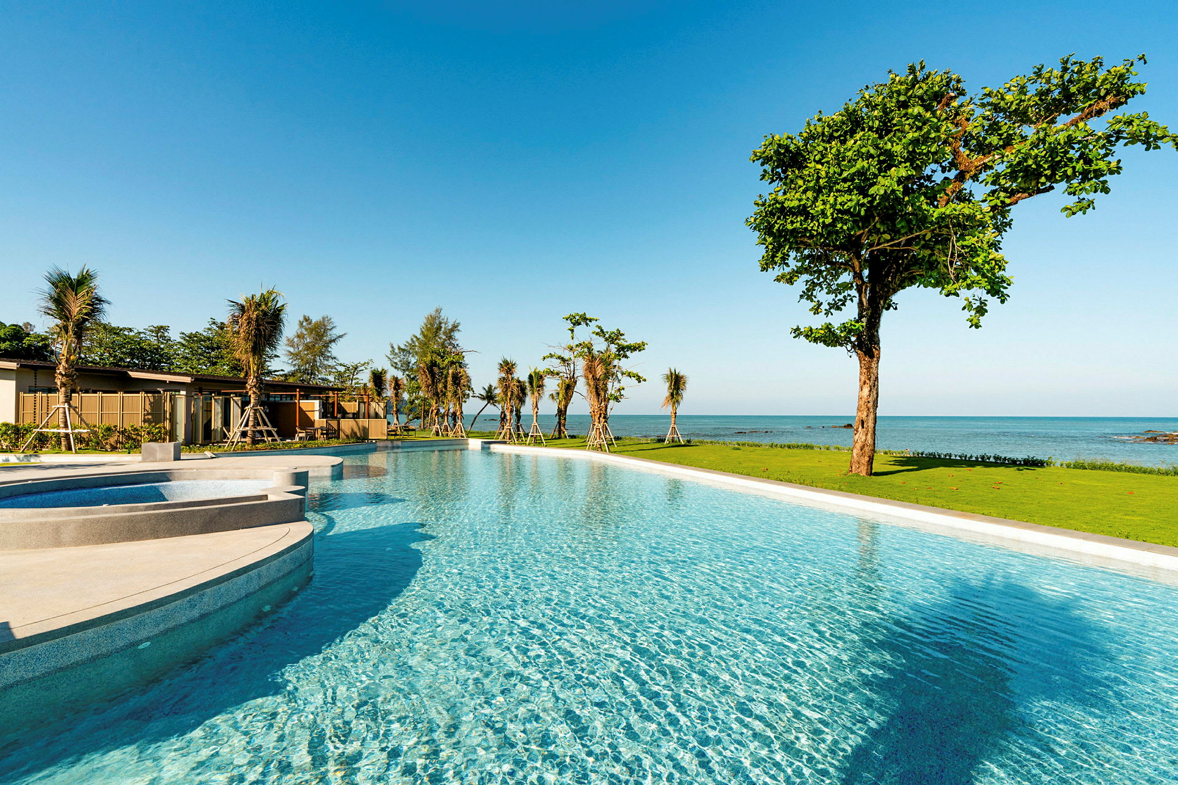 En pool og grønt område ved stranden med udsigt til havet. (AI-genereret tekst)