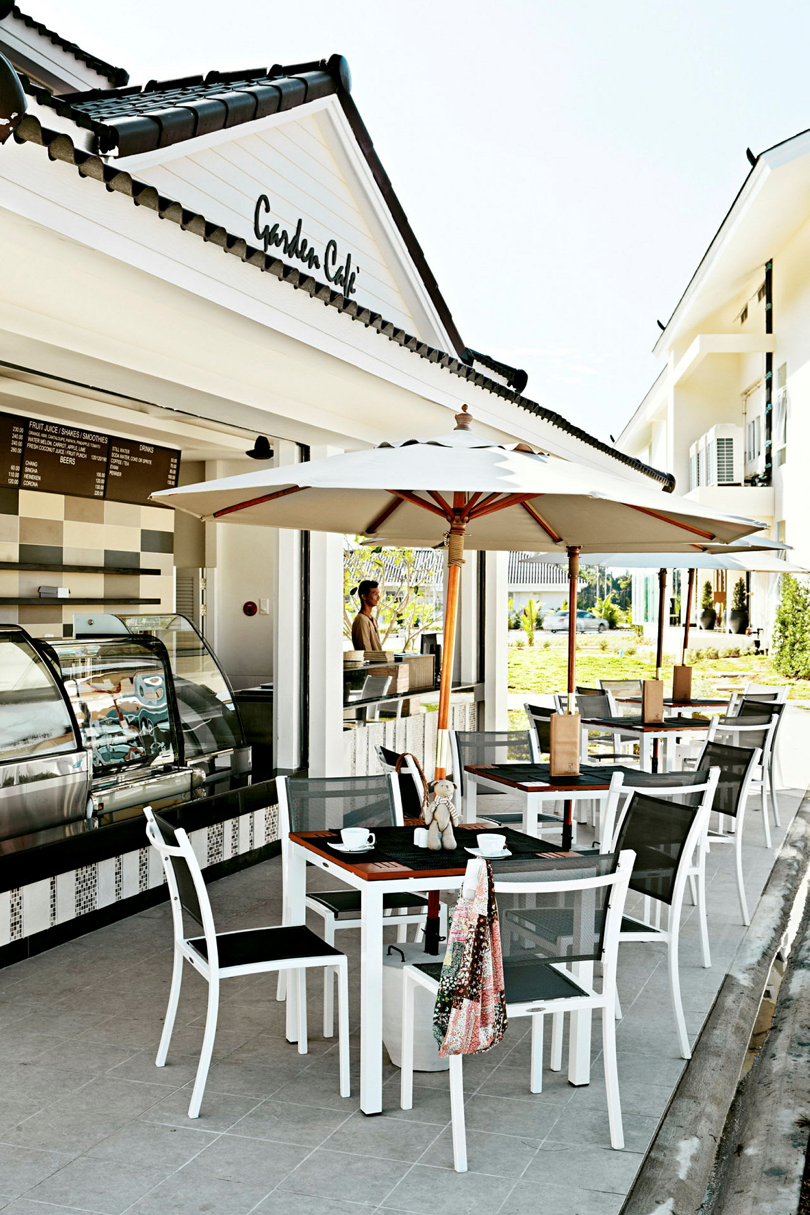 Udendørs terrasse med parasoller og borde ved en cafébygning. (AI-genereret tekst)