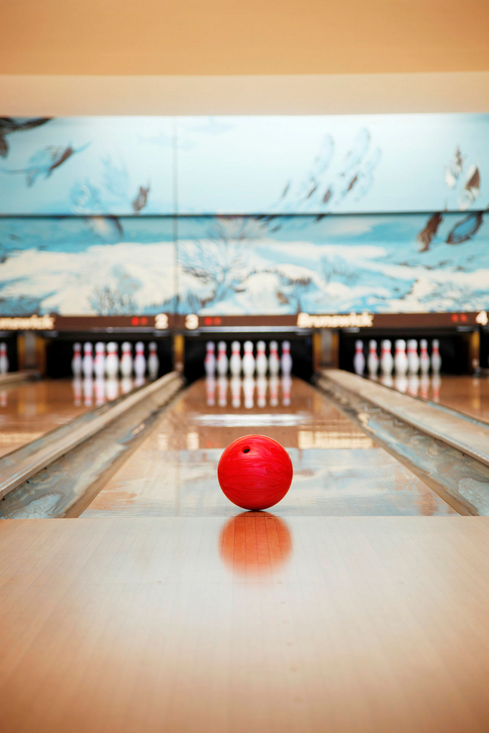 En rød bowlingkugle ligger på en bowlingbane, med kegler i baggrunden. (AI-genereret tekst)