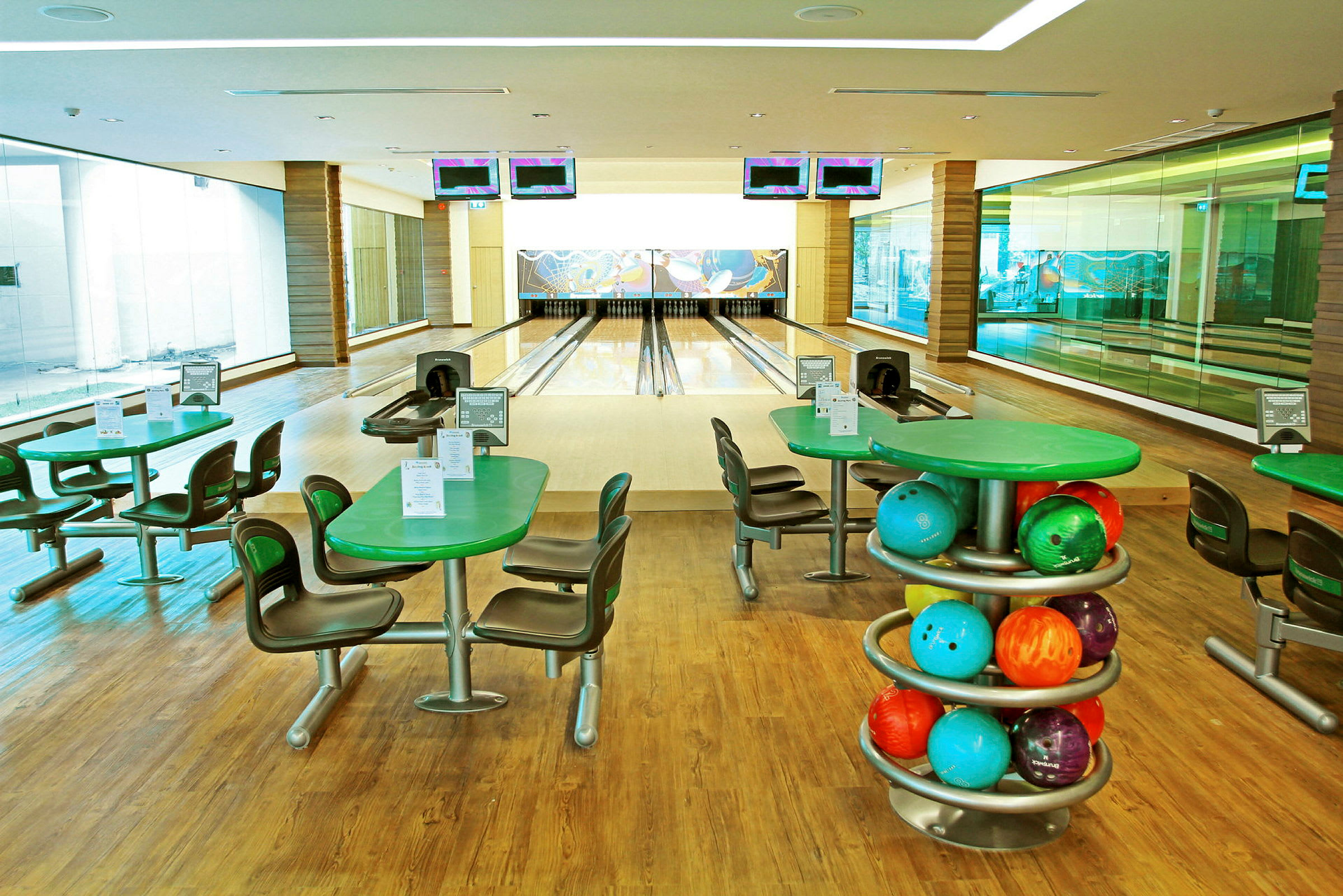 En bowlinghal med fire bowlingbaner, borde og stole samt farverige bowlingkugler. (AI-genereret tekst)