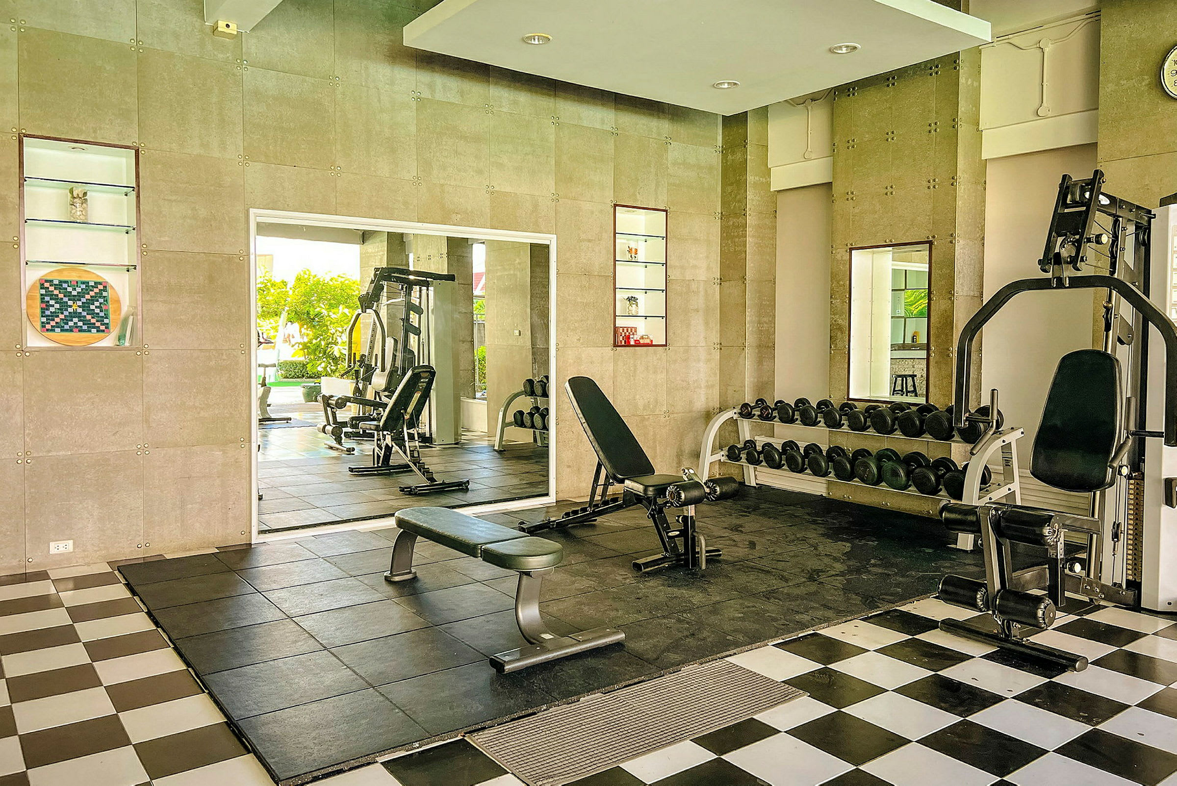 Billede af et fitnesscenter med træningsmaskiner, bænke og håndvægte. (AI-genereret tekst)