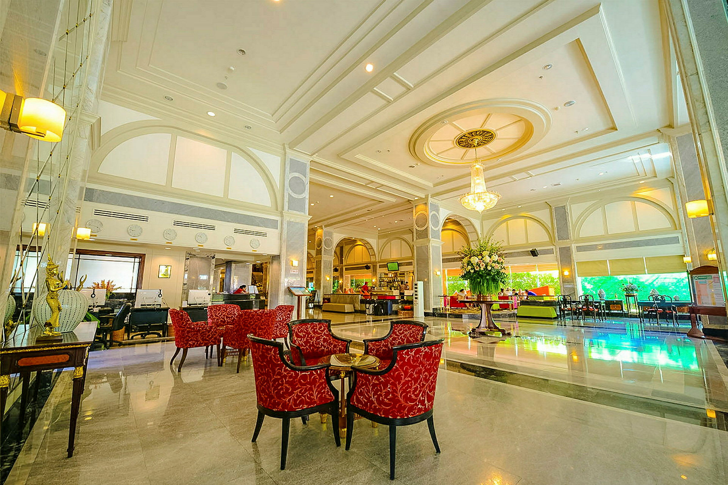 Elegant hotellobby med røde siddemøbler og en stor blomsterdekoration. (AI-genereret tekst)