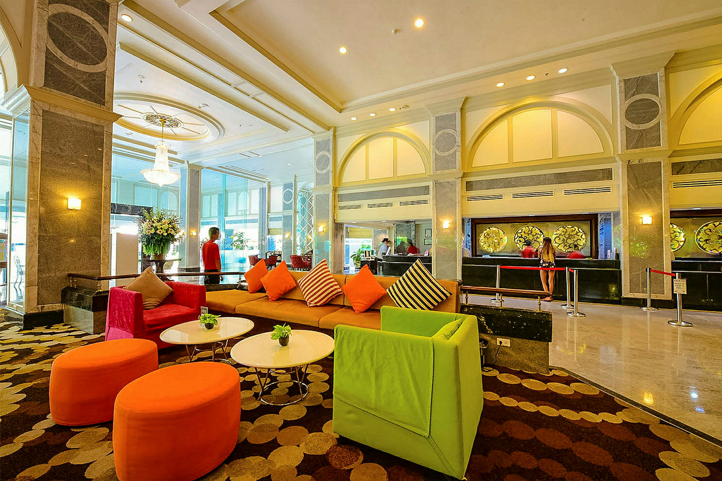 Interiør af en rummelig hotelreception med farverige siddepladser og receptionen i baggrunden. (AI-genereret tekst)