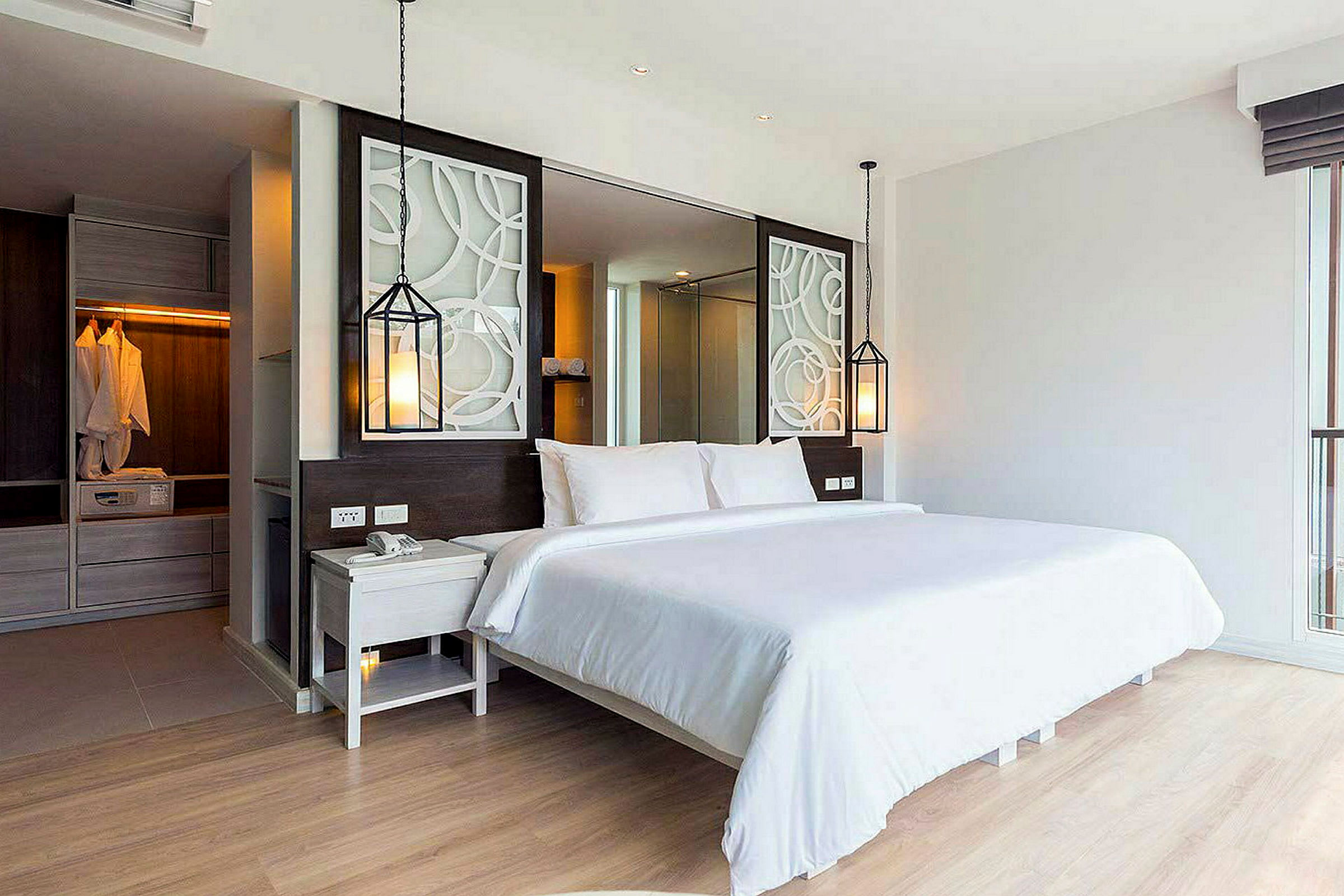 En moderne hotelsuite med en komfortabel dobbeltseng, dekorative elementer og et skab i baggrunden. (AI-genereret tekst)